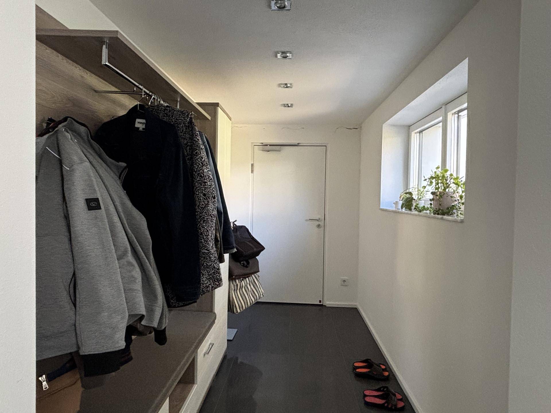 Schmaler Flur mit integrierter Garderobe und Fenster, das für natürliches Licht sorgt.