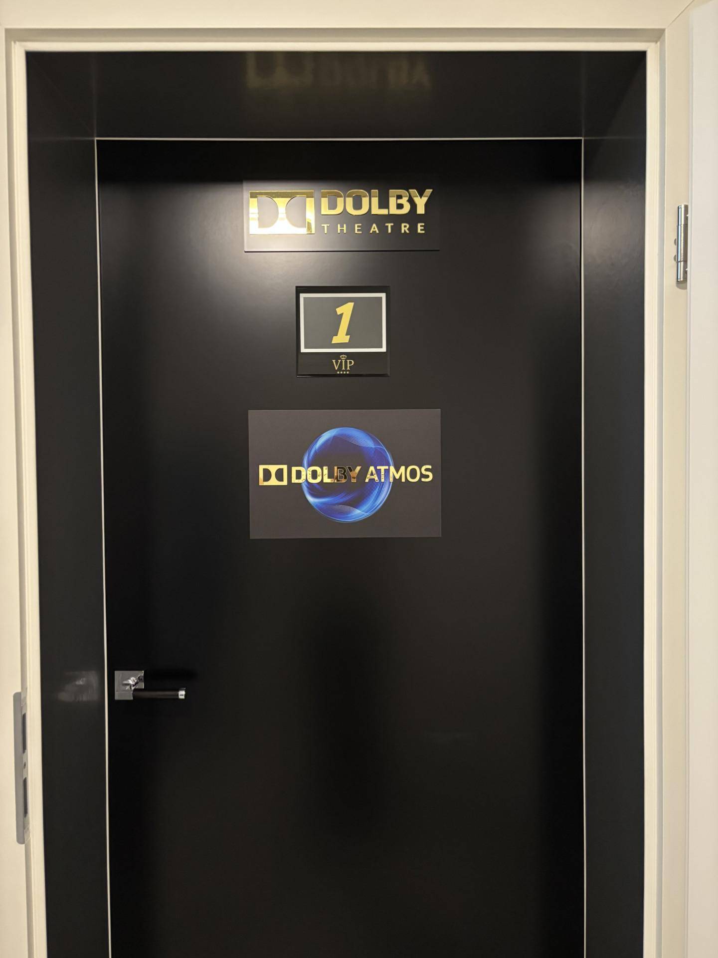Schwarze Tür mit Dolby Theatre und Dolby Atmos Beschriftung, die auf einen Kinoraum hinweist.