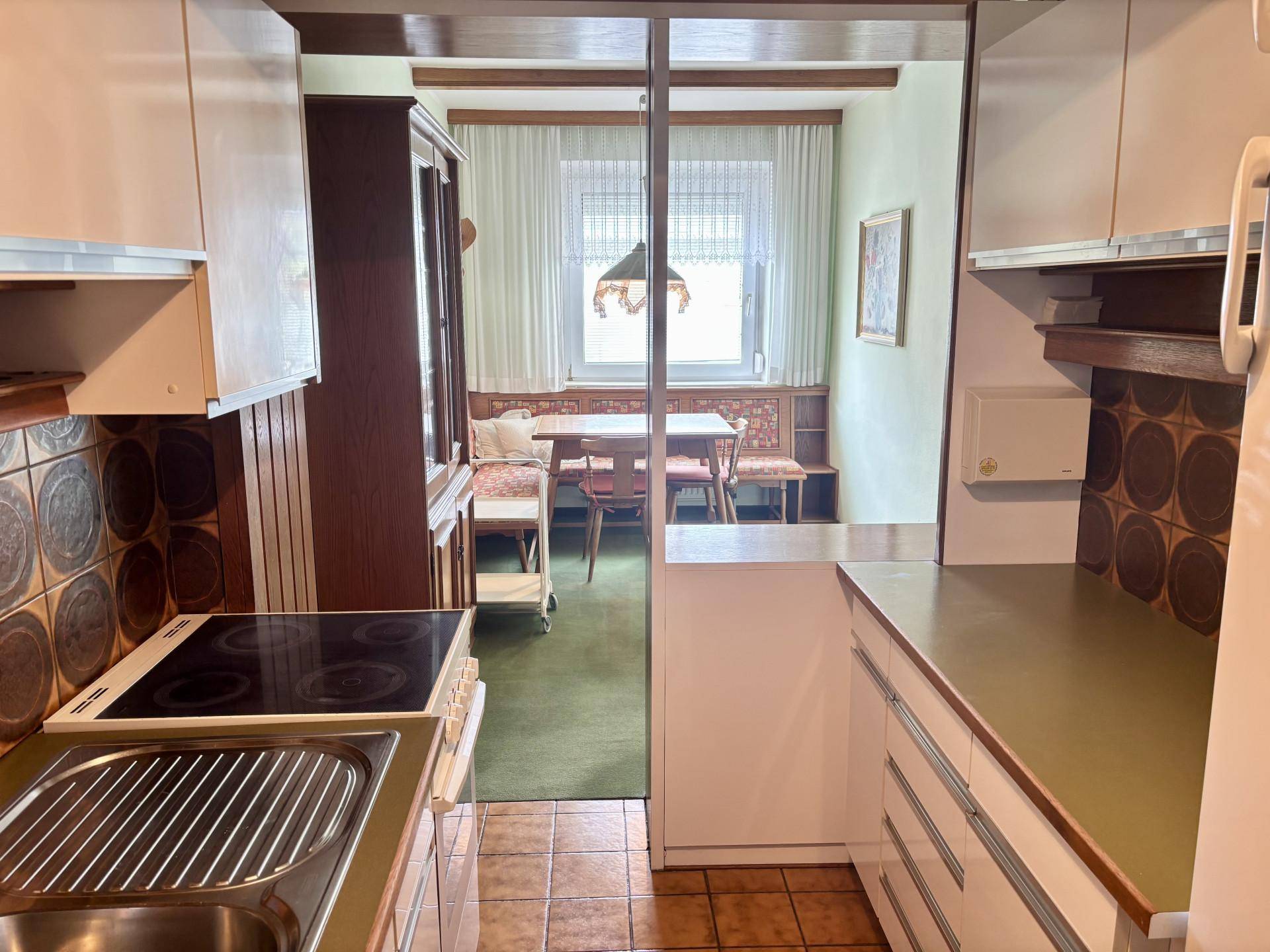 Halboffene Küche mit Blick in den Essbereich, ausgestattet mit Kochfeld und Spüle.