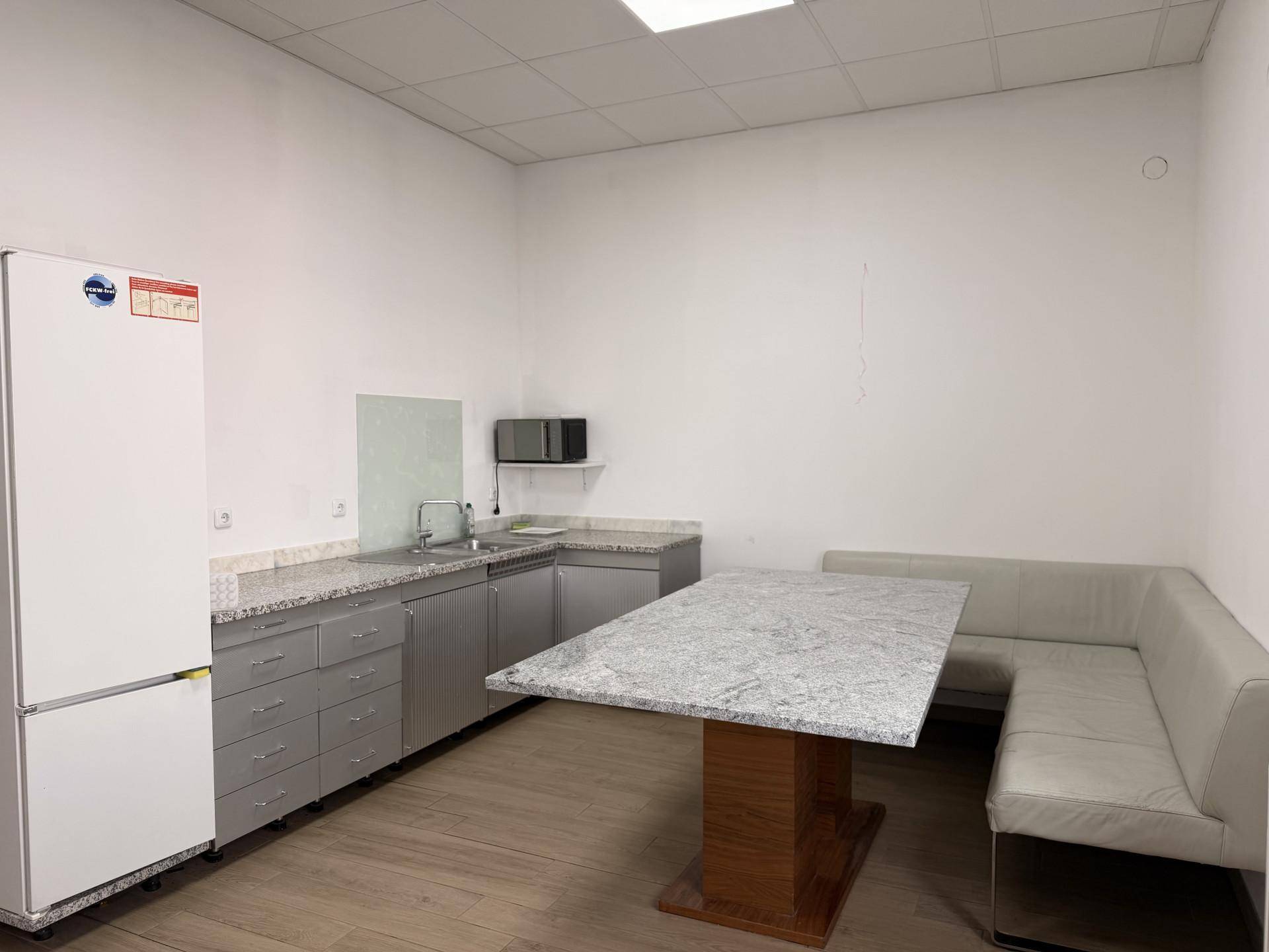 Funktionale Küchenzeile mit Essbereich, Kühlschrank und Mikrowelle in einem Pausenraum.