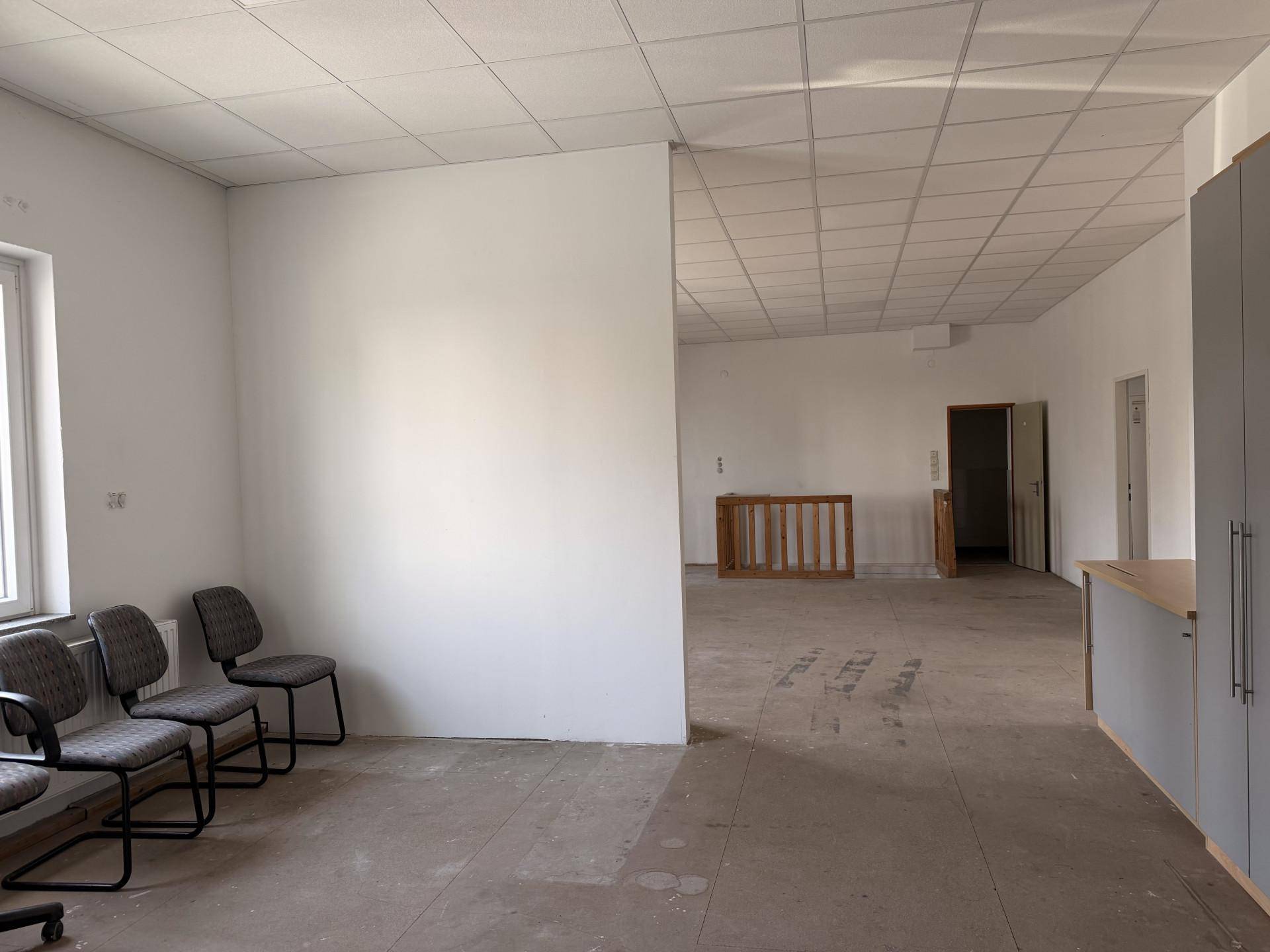 Geräumiger Gewerberaum mit Sitzgelegenheiten, abgehängter Decke und viel Platz.