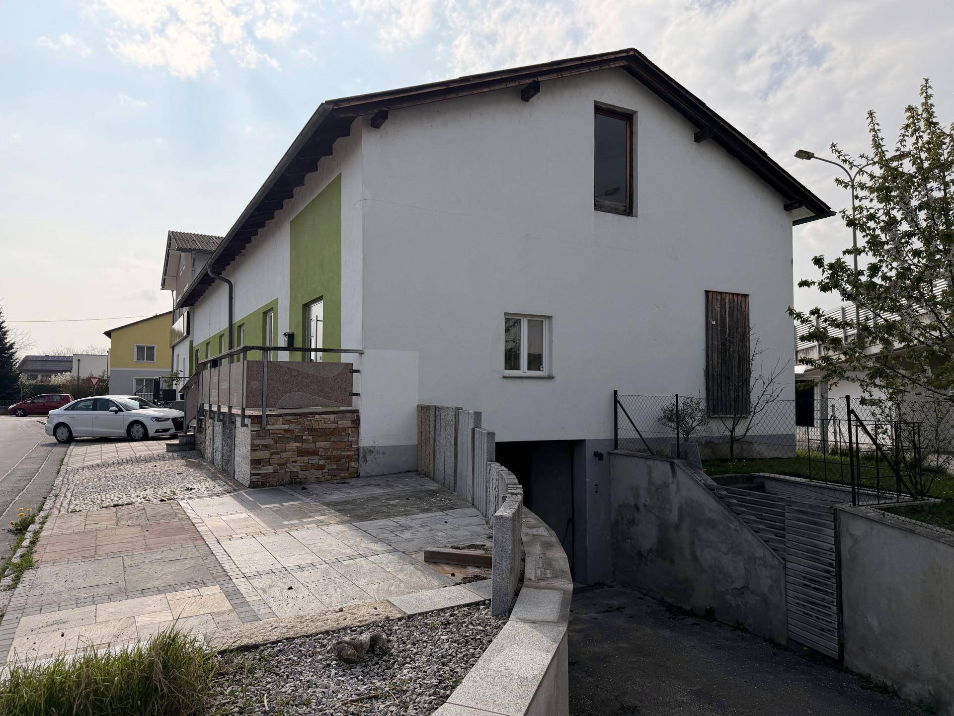 Außenansicht des Gebäudes mit Zufahrt zur Tiefgarage und grün-weißer Fassade.