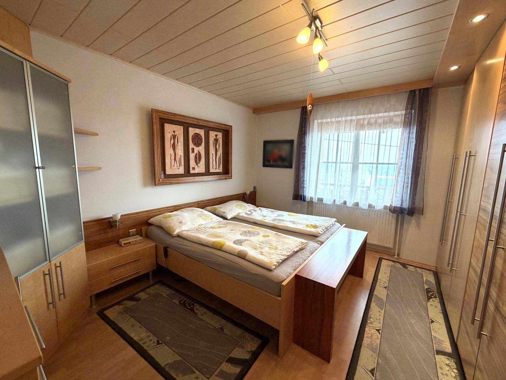 Schlafzimmer mit zwei Einzelbetten, Holzschränken und hellem Fenster.