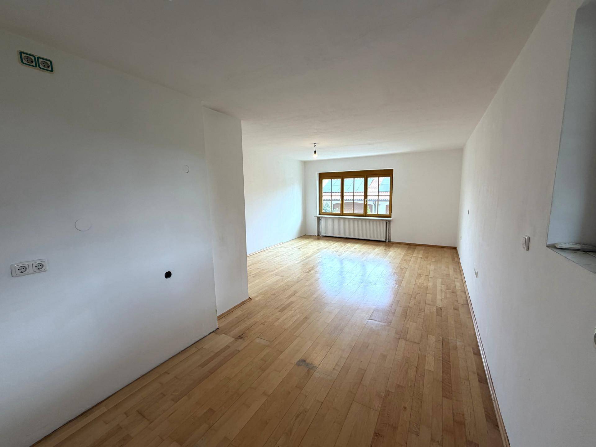Heller, unmöblierter Raum mit Holzboden und großem Fenster, ideal für individuelle Nutzung.