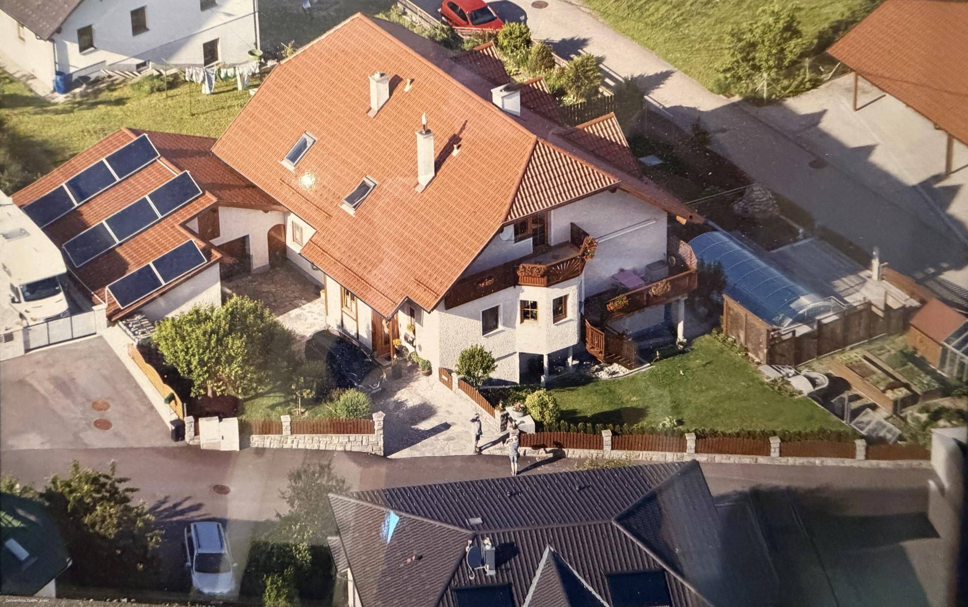 Luftaufnahme des Anwesens mit Photovoltaikanlage auf dem Dach und umliegender Bebauung.