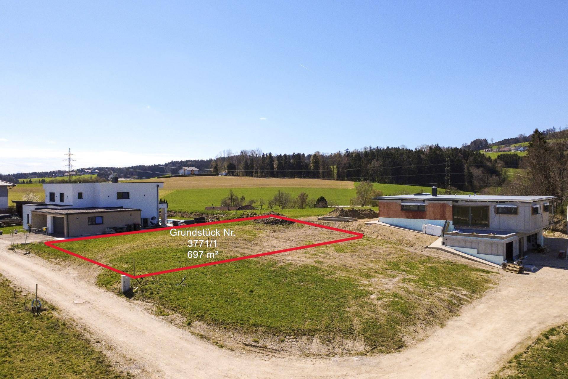 Übersicht über ein Baugrundstück mit roter Markierung und angrenzenden Neubauten in ländlicher Umgebung.