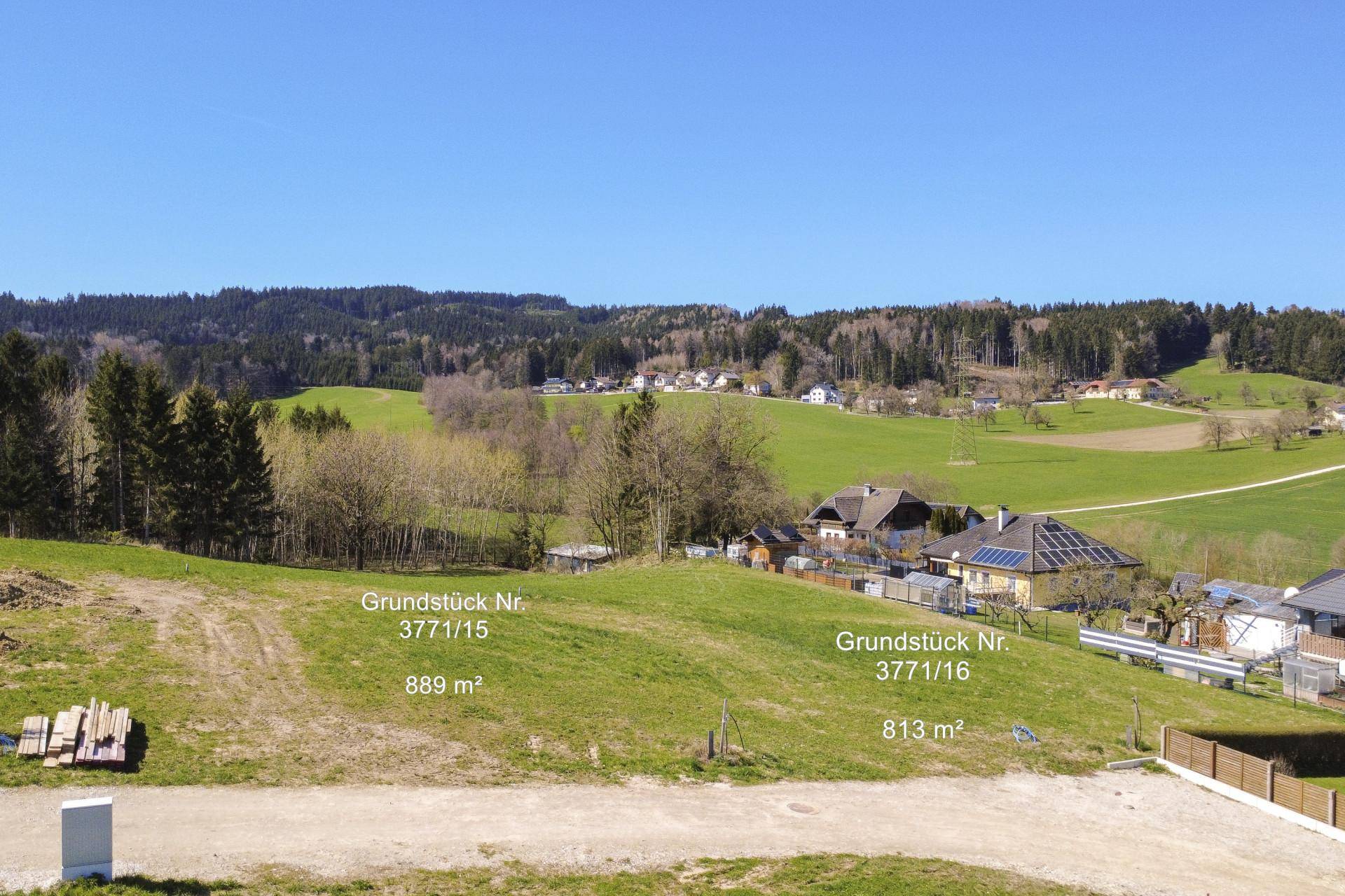 Weitläufige Ansicht mehrerer Baugrundstücke mit Blick auf die hügelige Landschaft und umliegende Häuser.
