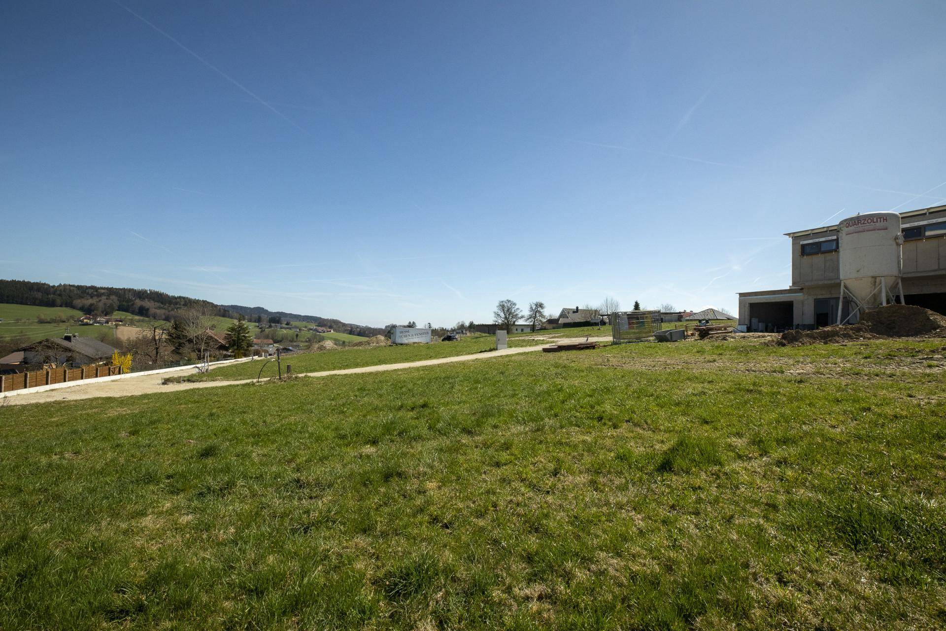 Weitläufiges Baugrundstück mit Blick auf die hügelige Landschaft und ein im Bau befindliches Gebäude.