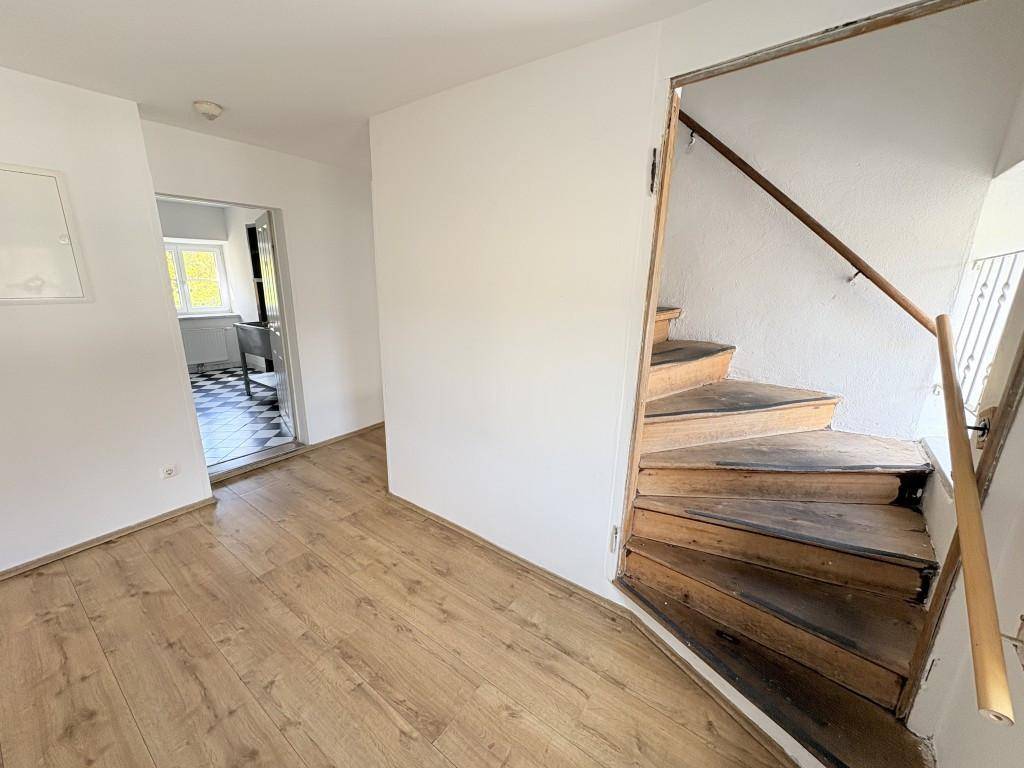 Flur mit Holzboden und einer rustikalen Holztreppe, die in die obere Etage führt.