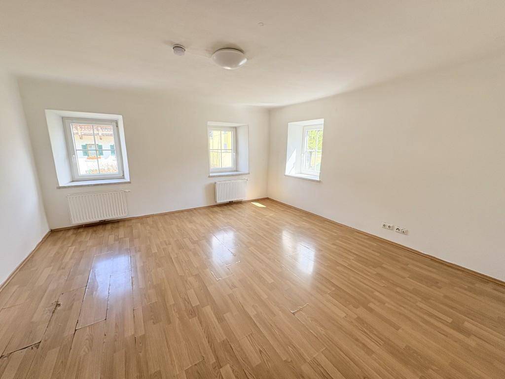 Heller, leerer Raum mit Holzboden und weißen Wänden, ideal für individuelle Gestaltung.