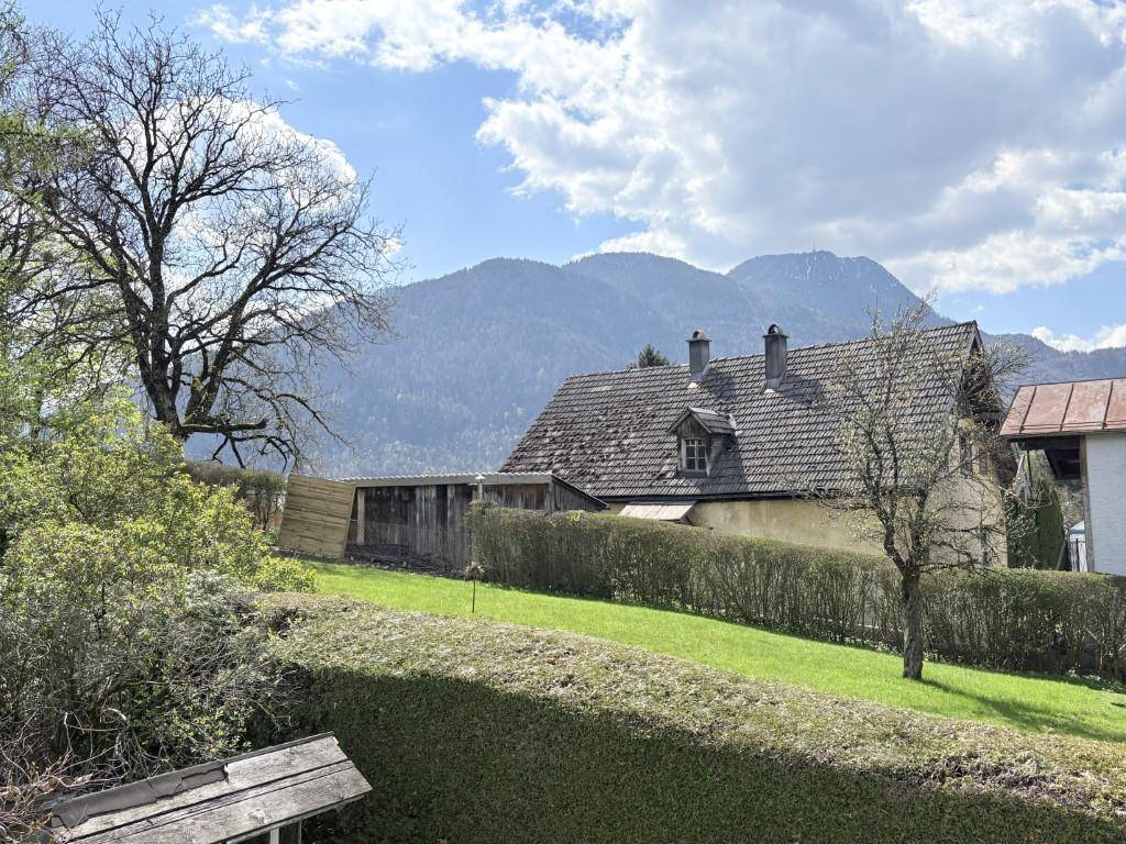 Malerischer Blick auf die Berge und ein Nachbarhaus über eine gepflegte Hecke.