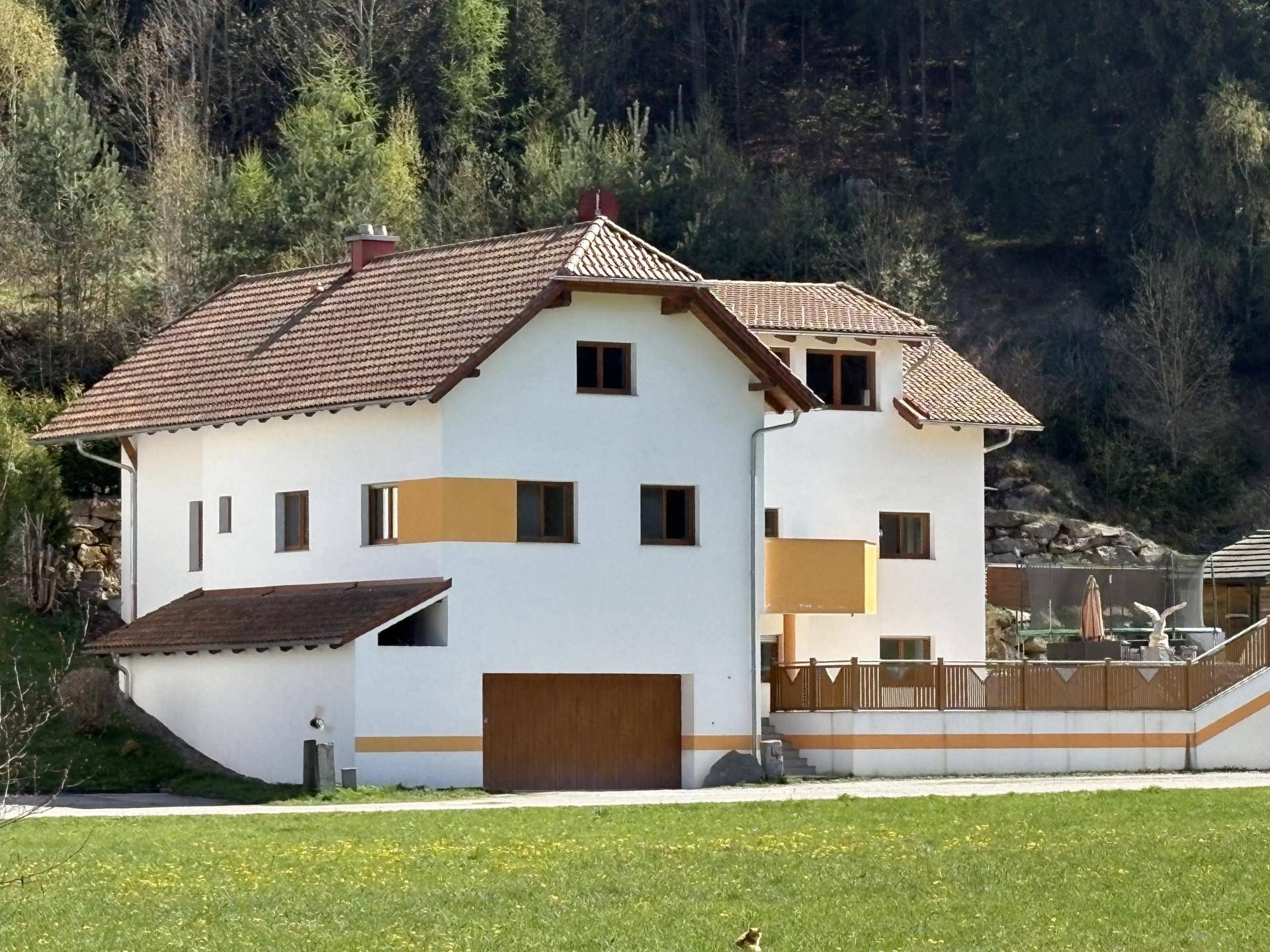 Attraktives Wohnhaus mit weißer Fassade, orangefarbenen Akzenten und Satteldach.