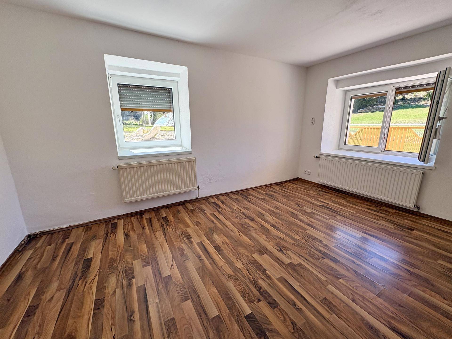 Helles Schlafzimmer mit attraktivem Holzboden und Fenstern mit Rollläden.