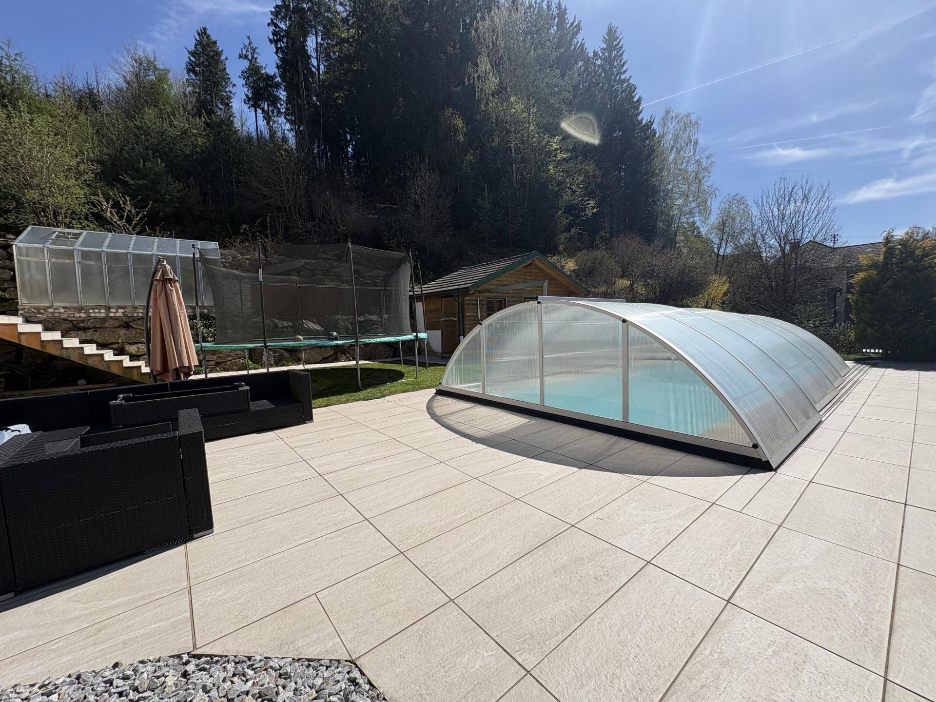 Sonniger Terrassenbereich mit bequemen Sitzgelegenheiten und überdachtem Pool.