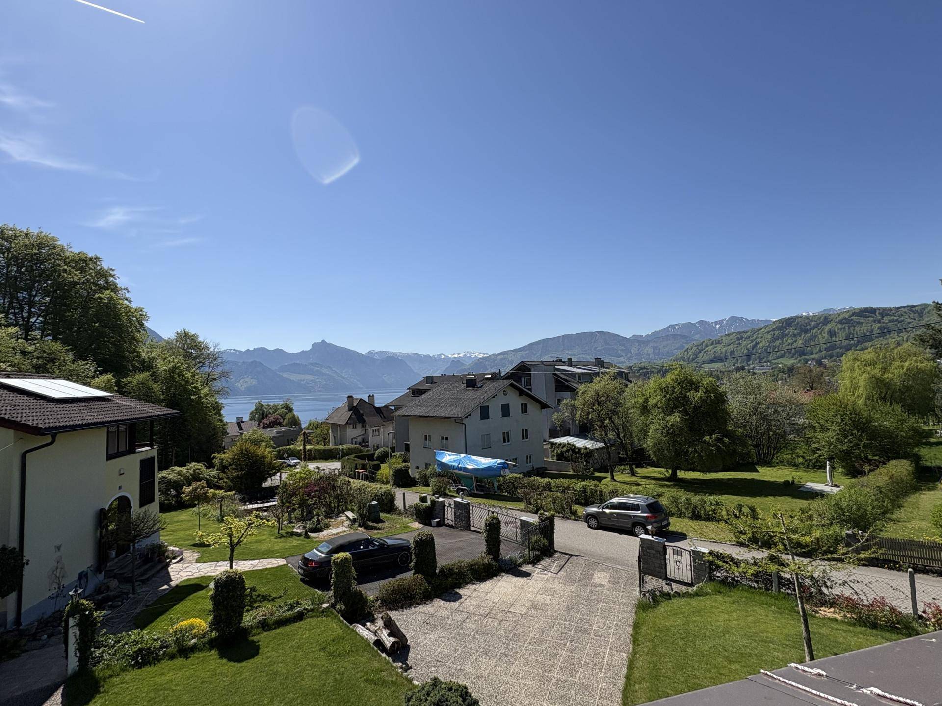 Panoramablick über die Nachbarschaft mit Häusern, See und majestätischen Bergen im Hintergrund.