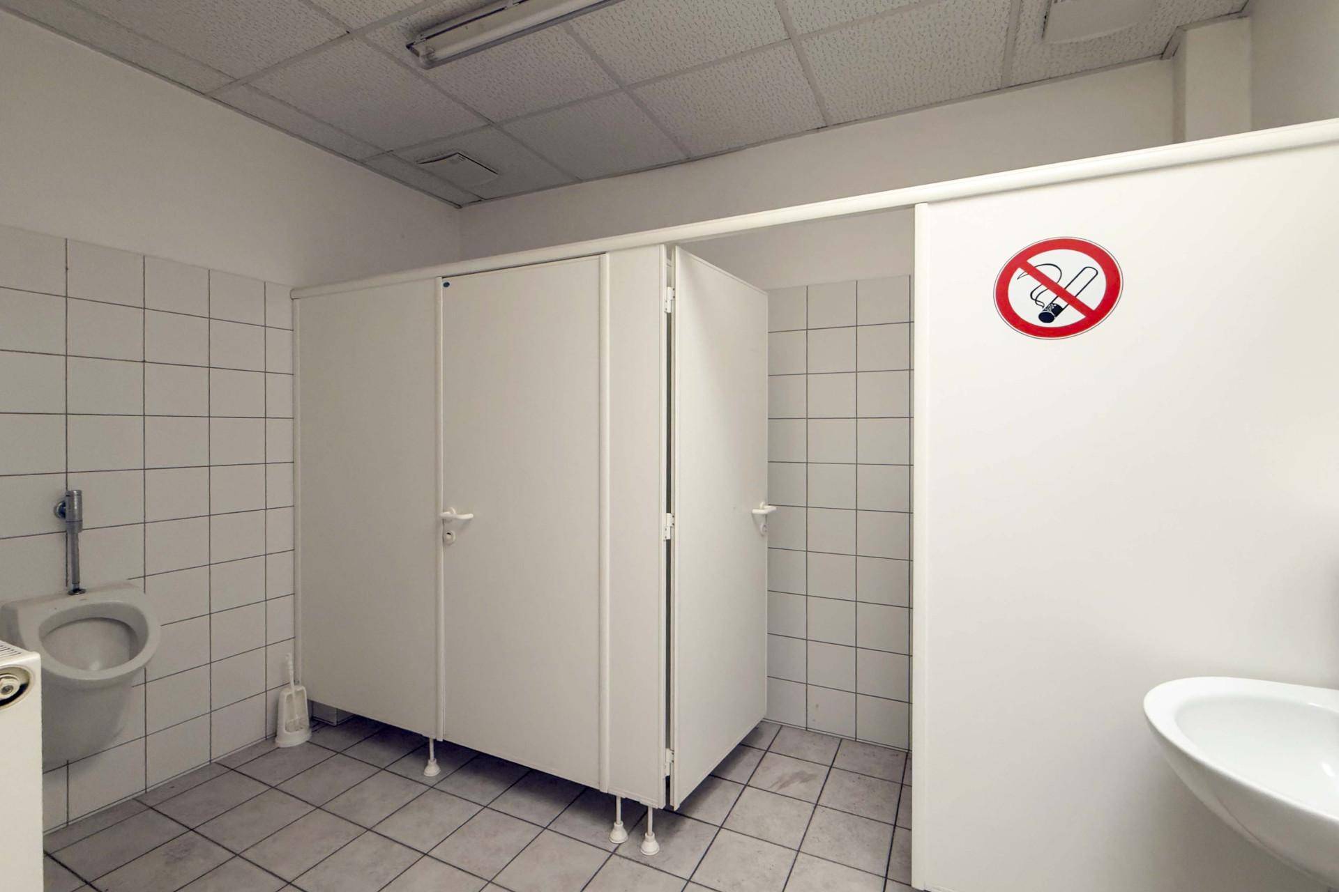Funktionaler Sanitärbereich mit Fliesenboden, Urinalen und Toilettenkabinen, in sauberem Zustand.