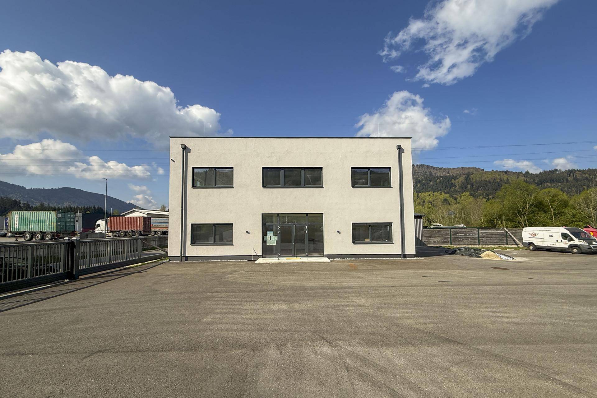 Außenansicht eines modernen Geschäftsgebäudes mit großem Parkplatz und blauer Himmel.