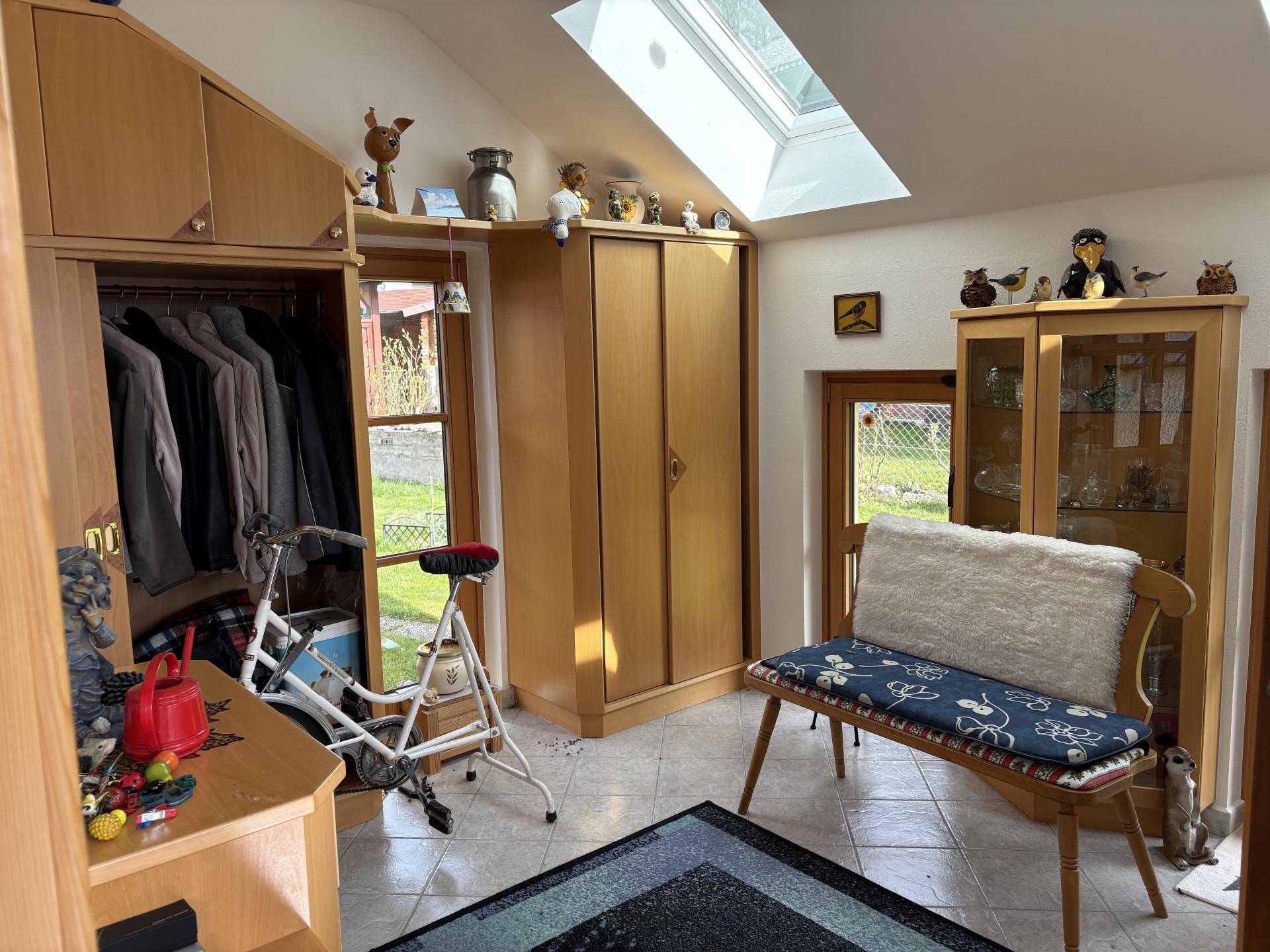 Heller Raum mit Dachschräge, Dachfenster und Einbauschränken, mit Blick in den Garten.
