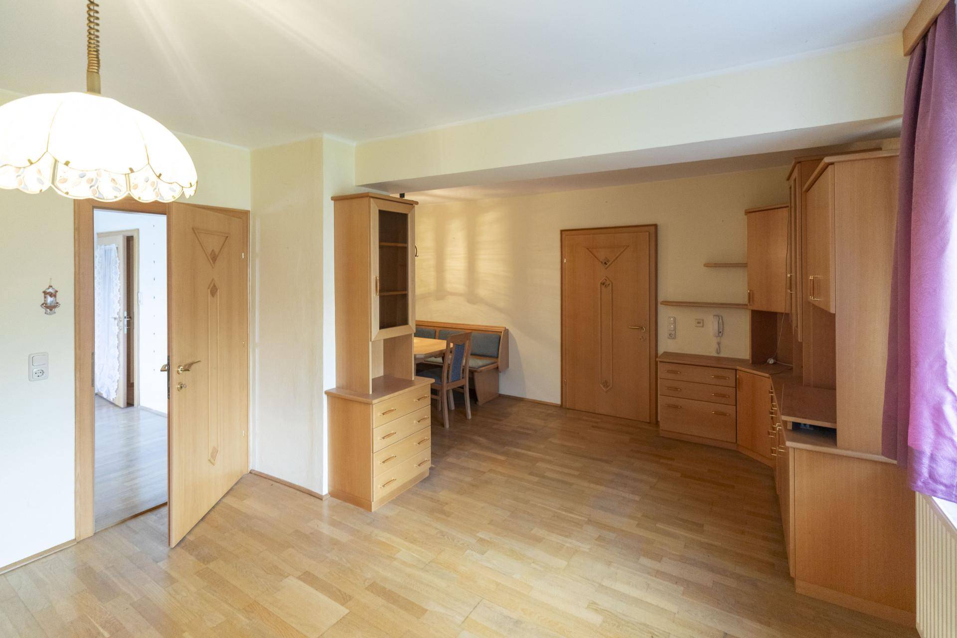 Heller Wohnbereich mit Holzboden, Holzmöbeln und einem integrierten Essbereich.