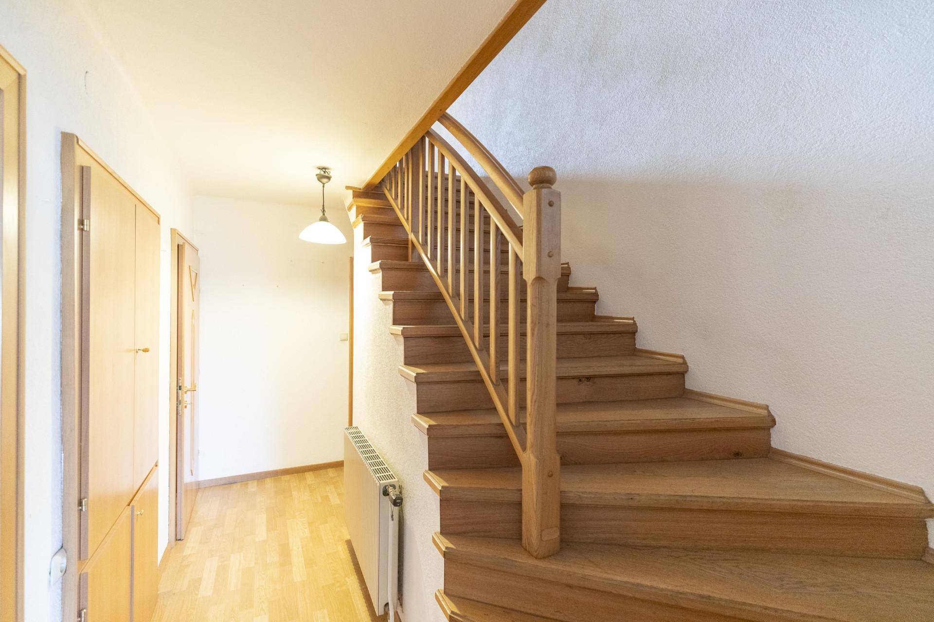 Heller Flur mit Holztreppe und Holzboden, der zu den oberen Etagen führt.