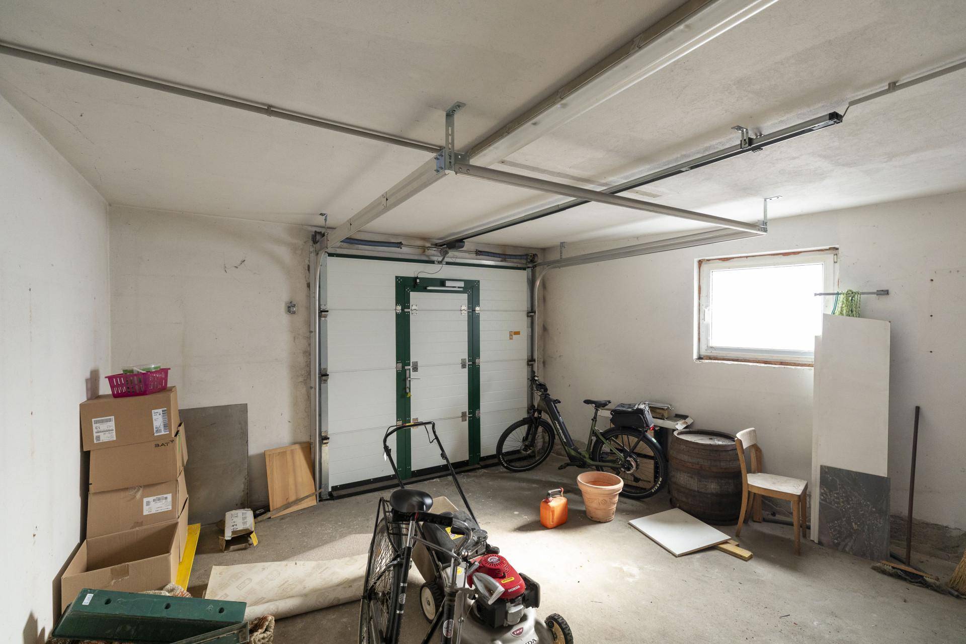 Geräumige Garage mit Betonboden, Garagentor und einem Fenster, genutzt als Abstellraum.