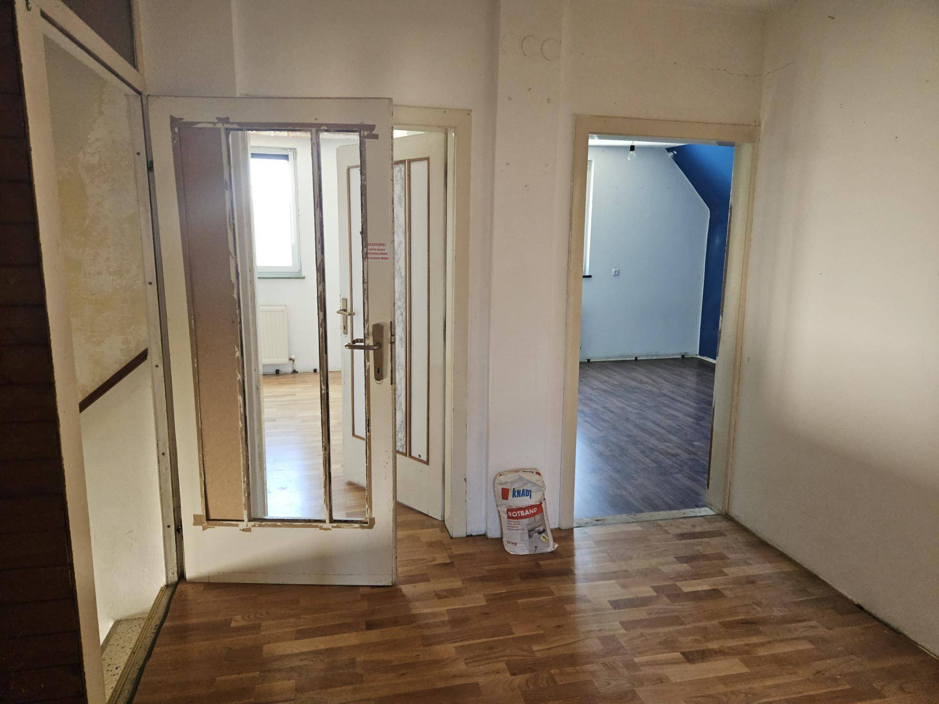 Flur mit Holzboden und mehreren Türen, die zu verschiedenen Räumen führen.