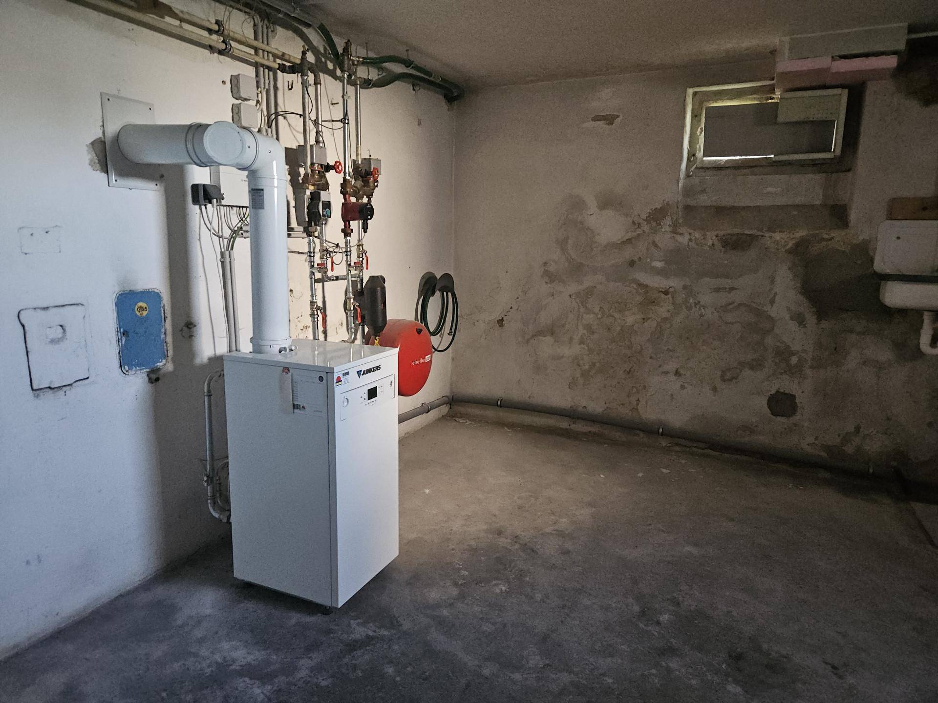 Heizungsraum im Keller mit moderner Heizungsanlage und sichtbaren Installationen.