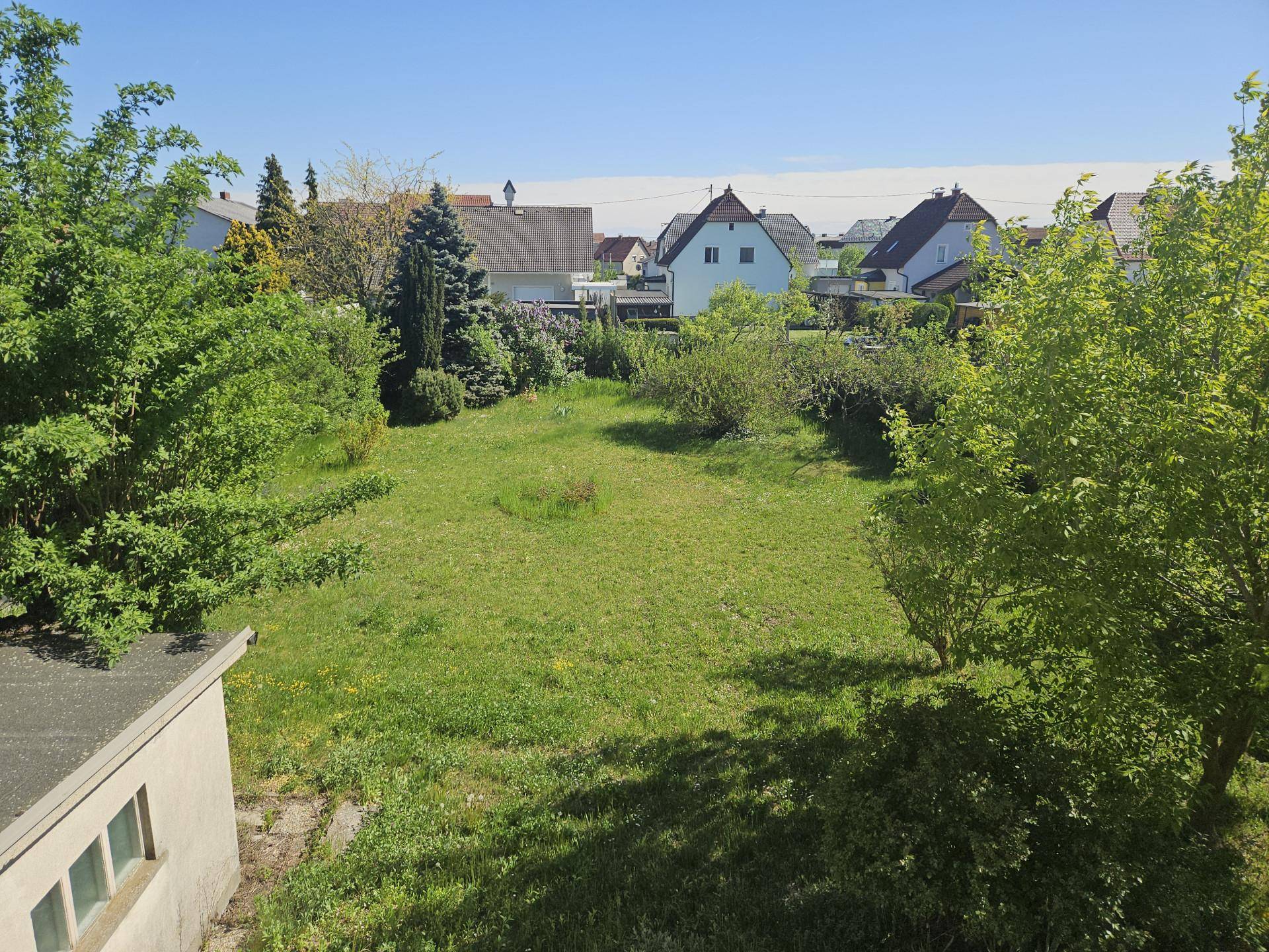 Weitläufiger Gartenbereich von oben gesehen, umgeben von Bäumen und anderen Häusern.