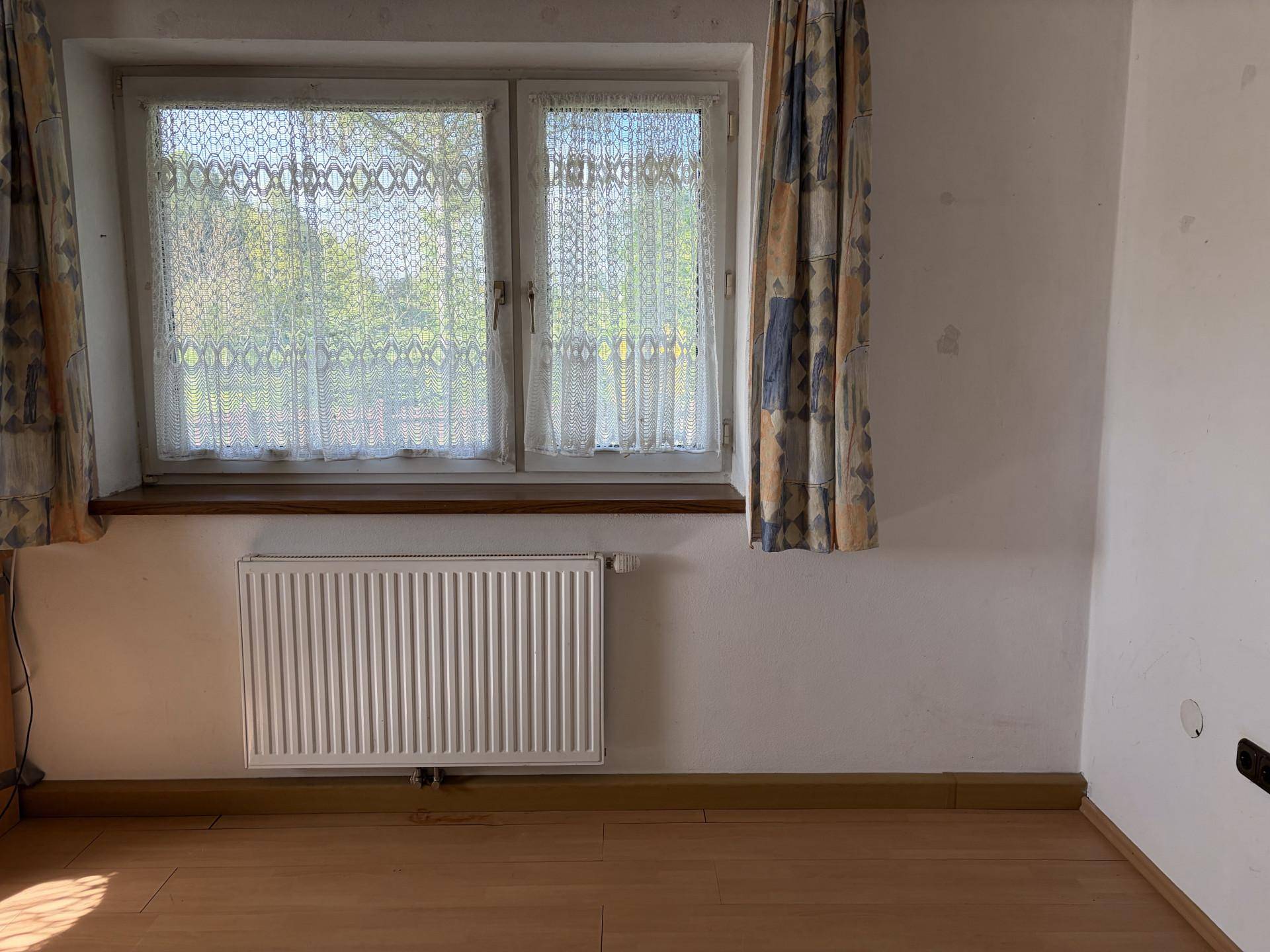 Heller Raum mit Fenster und Heizkörper, bereit für individuelle Gestaltung und Nutzung.