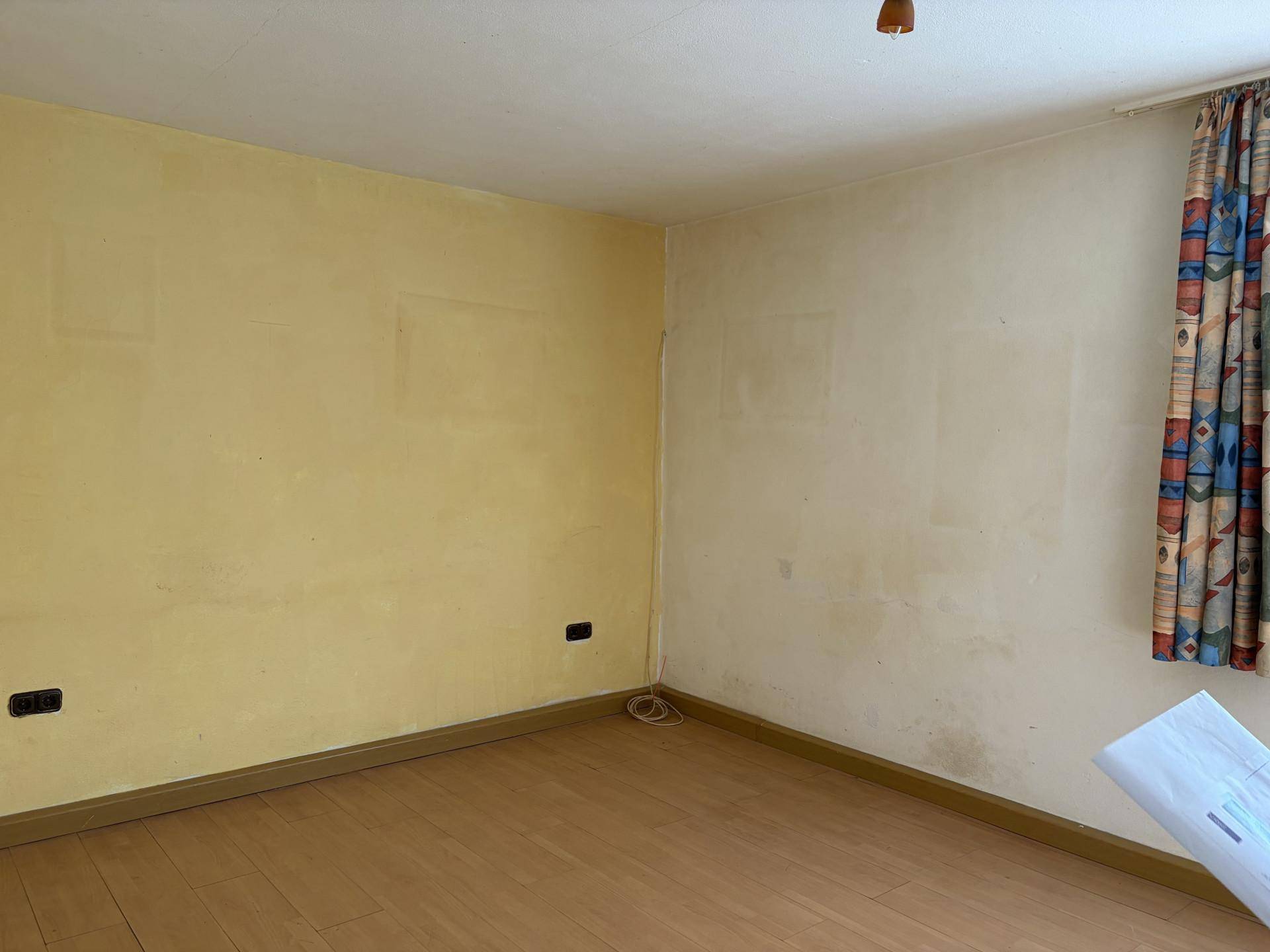 Leeres Schlafzimmer mit Laminatboden und gelben Wänden, bereit zur individuellen Einrichtung.