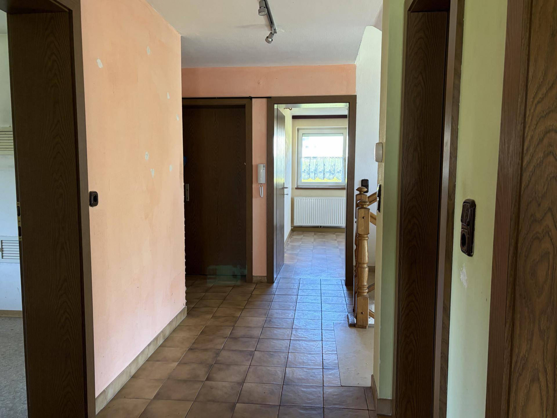 Flur mit Fliesenboden und Holztüren, führt zu verschiedenen Räumen im Haus.