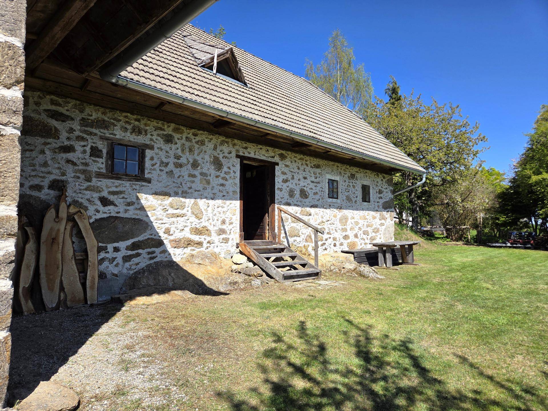 Detailansicht des historischen Steinhauses mit rustikaler Holztür und kleinen Fenstern.