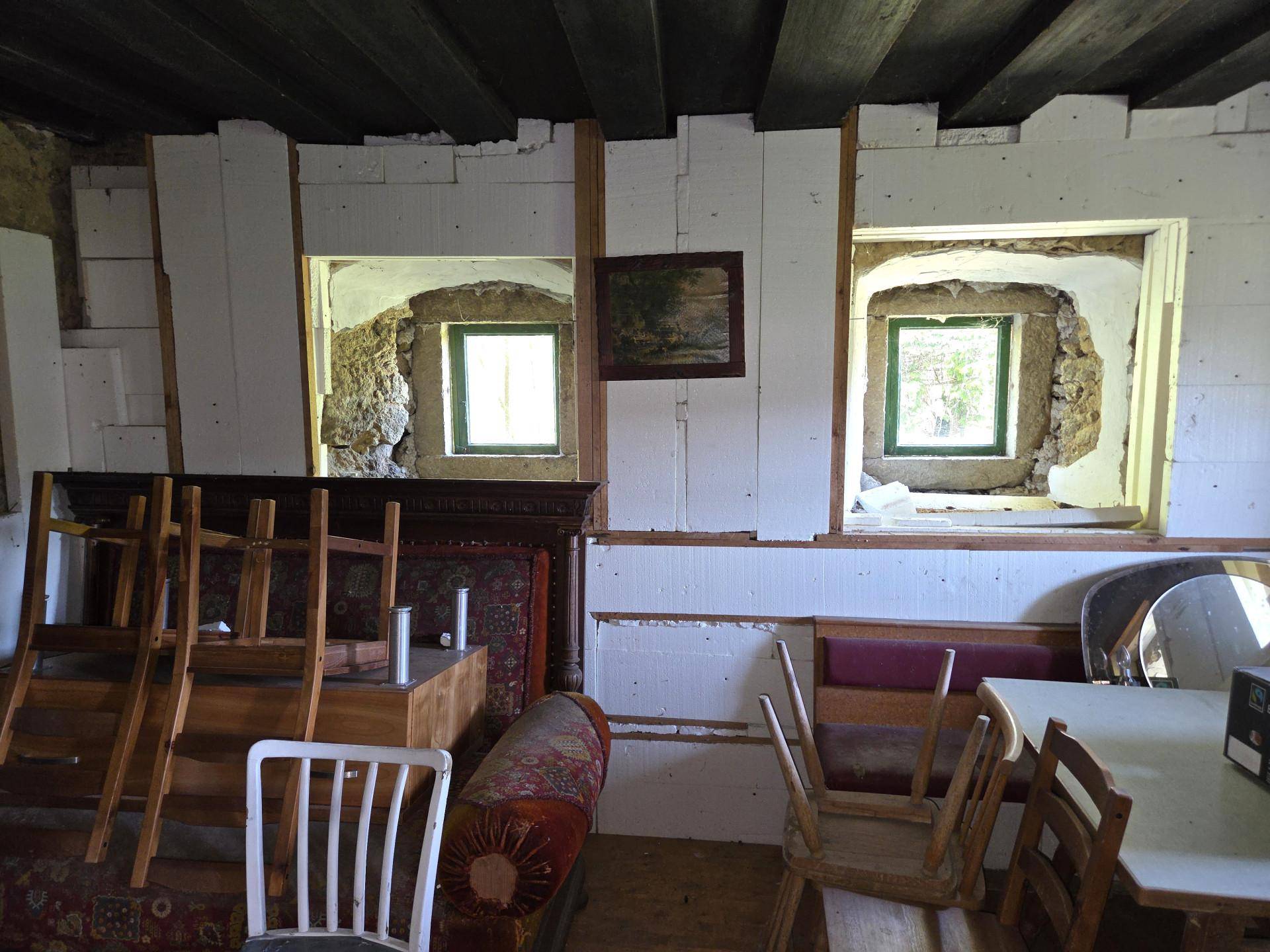 Unfertiger Innenraum mit freigelegten Steinwänden und Holzdecke, bereit zur Renovierung und Gestaltung.