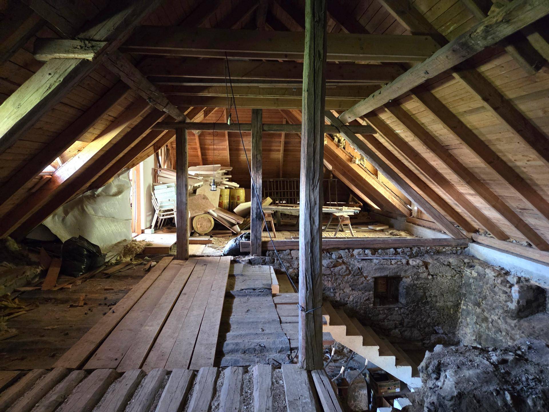 Weitläufiger Dachboden mit sichtbarer Holzkonstruktion und viel natürlichem Licht, ideal für Ausbau.