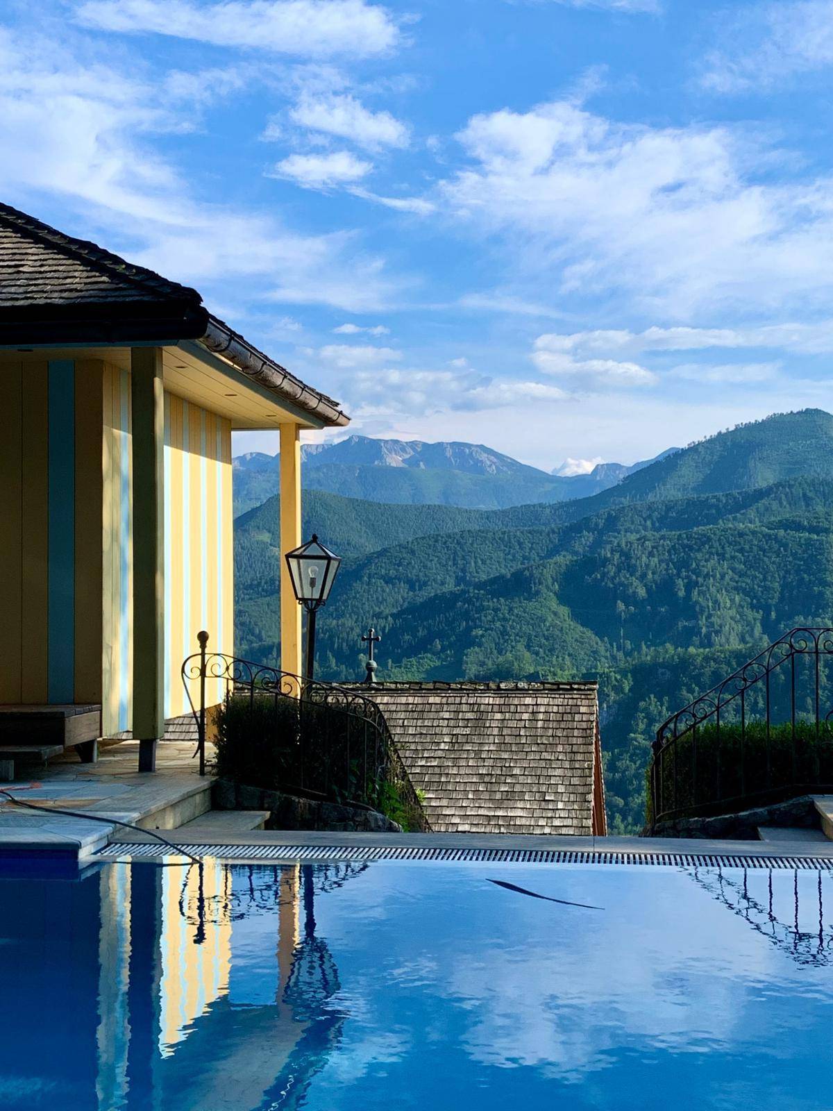 Infinity-Pool mit atemberaubendem Blick auf die grüne Berglandschaft und den blauen Himmel.