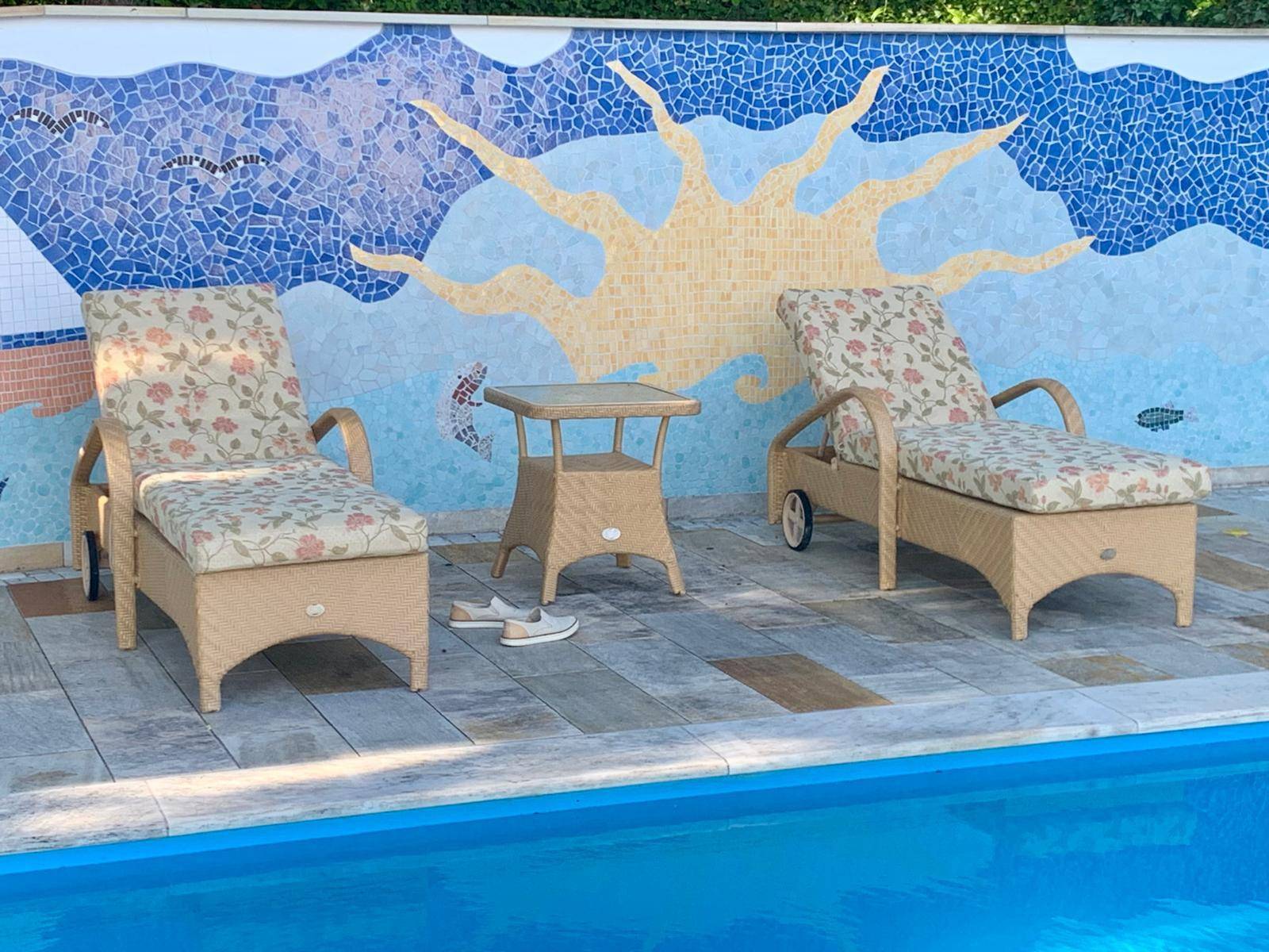 Entspannender Poolbereich mit Liegestühlen und einer farbenfrohen Mosaikwand.