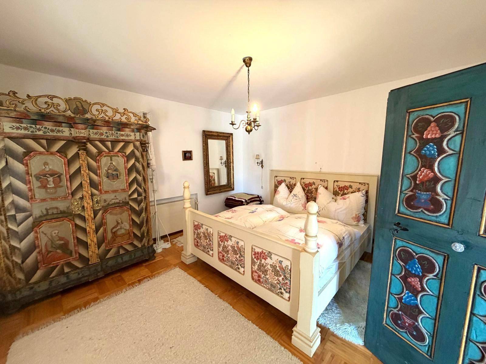 Schlafzimmer mit handbemaltem Bett und Kleiderschrank im traditionellen Landhausstil.