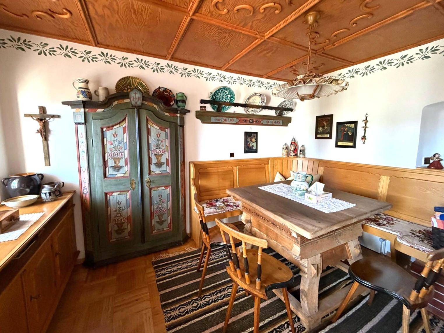 Gemütlicher Essbereich im alpinen Stil mit handbemaltem Schrank und geschnitzter Holzdecke.