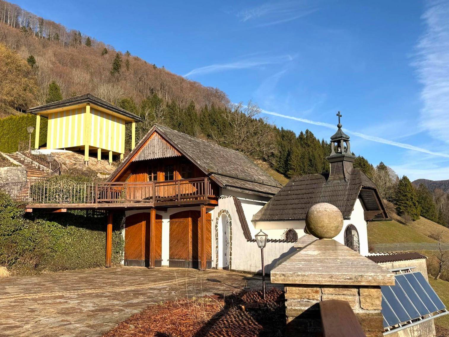 Traditionelle Nebengebäude und eine kleine Kapelle mit Solaranlage in ländlicher Umgebung.