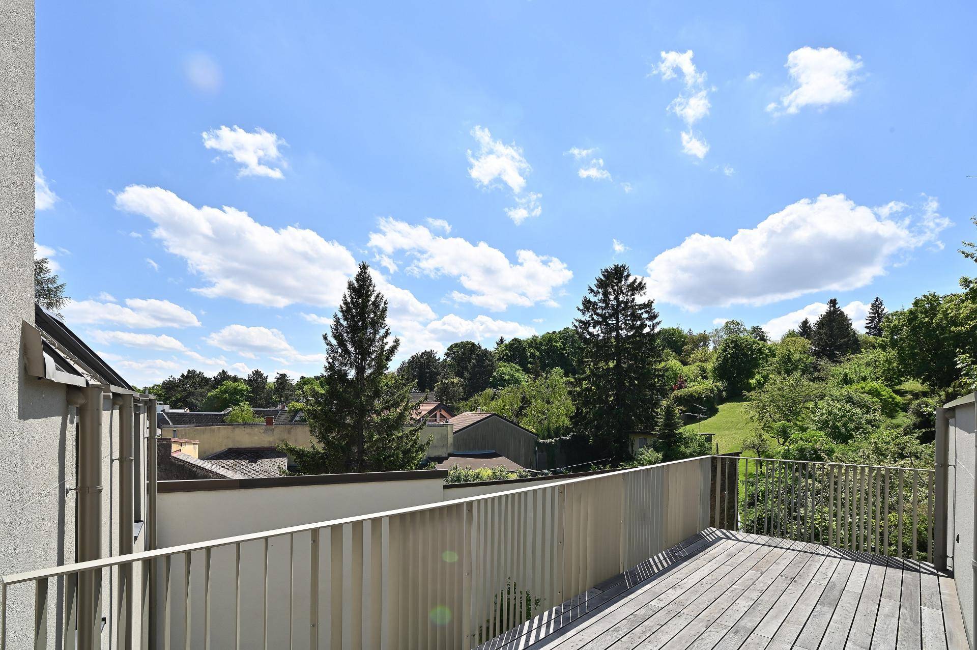 Großer Balkon mit Holzboden und weitem Blick ins Grüne und auf die Umgebung.