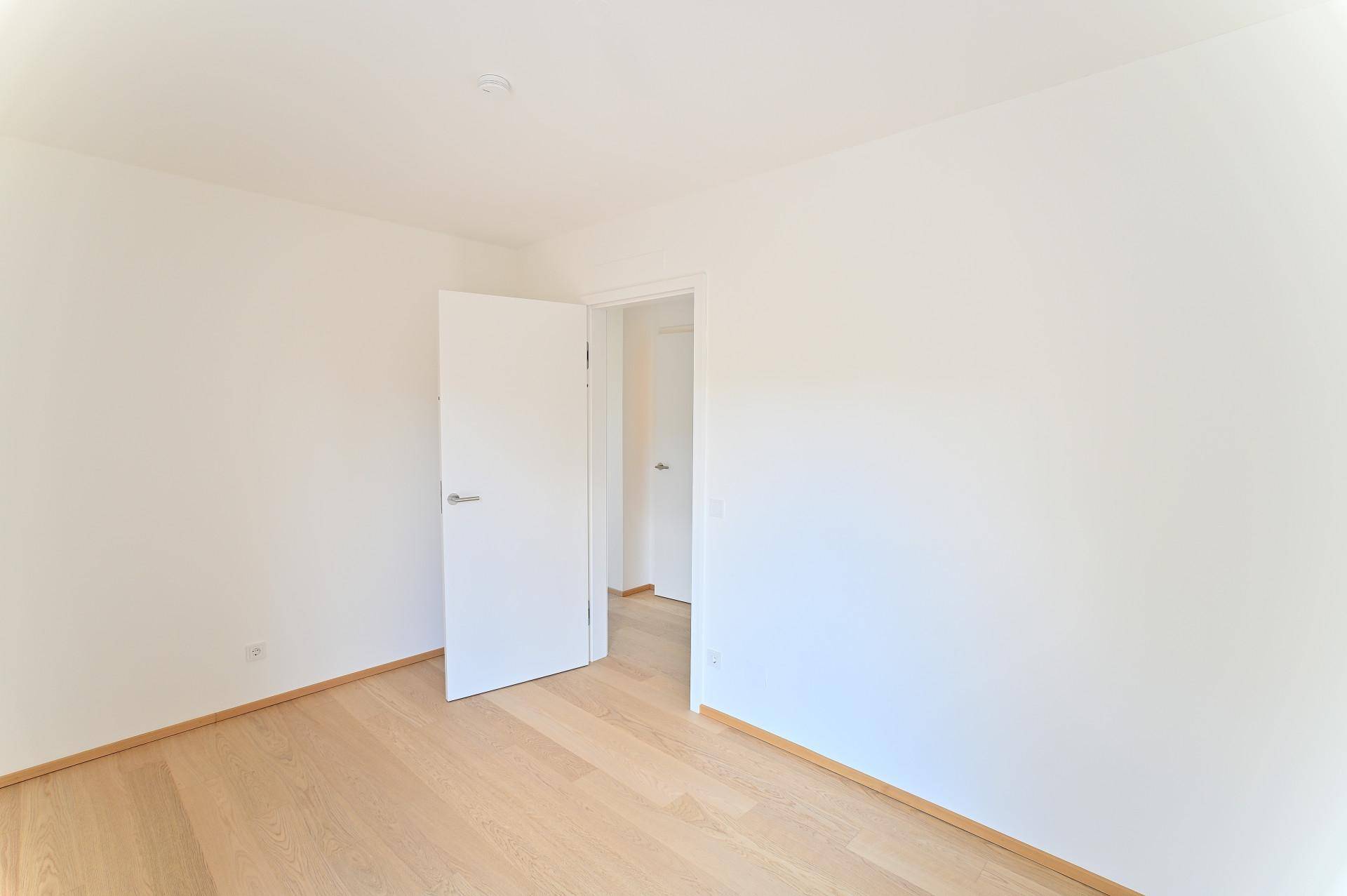 Leeres Schlafzimmer mit hellem Holzboden und weiß gestrichenen Wänden.