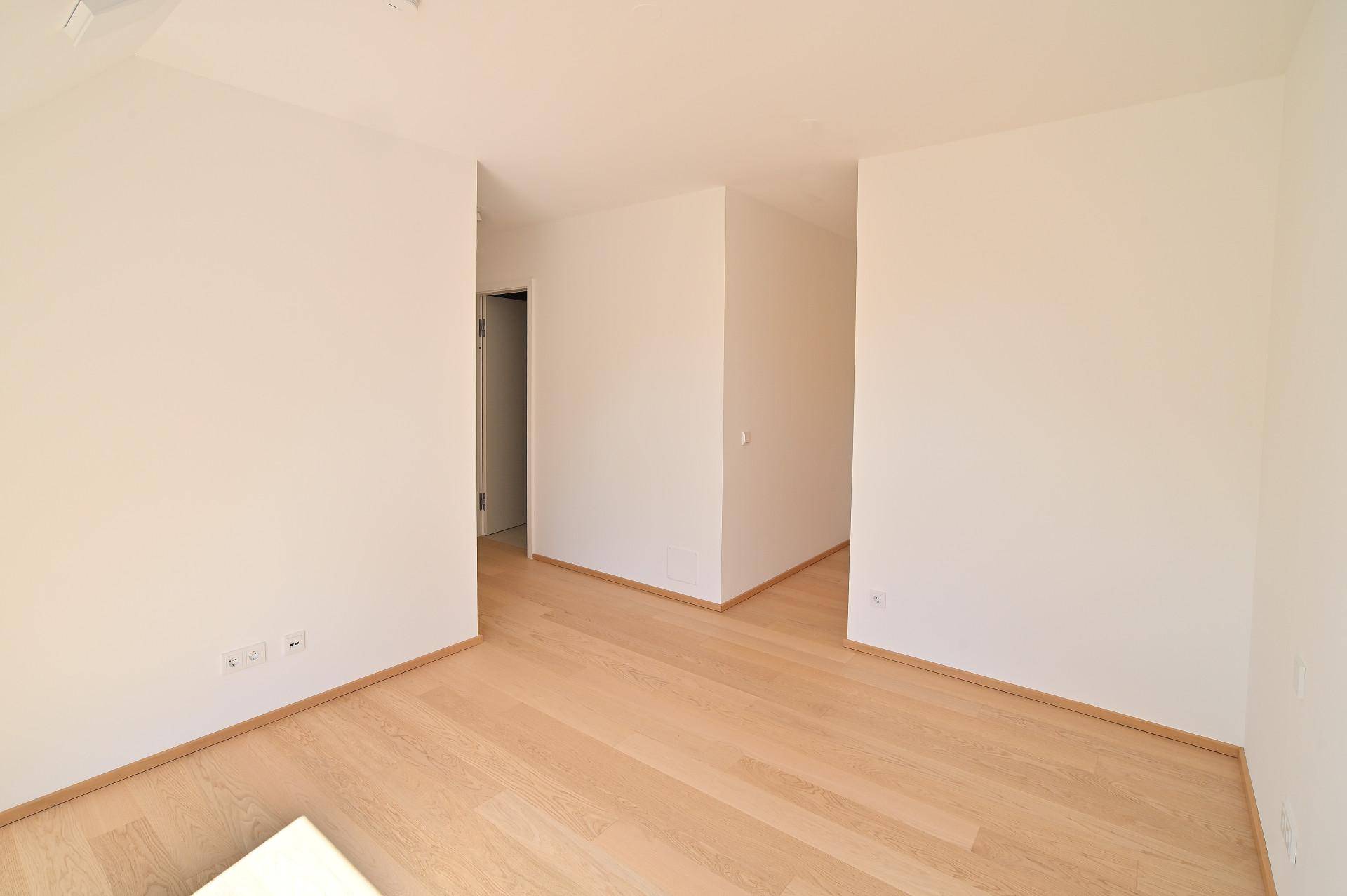 Heller Flur mit Holzboden und weiß gestrichenen Wänden, der zu weiteren Räumen führt.