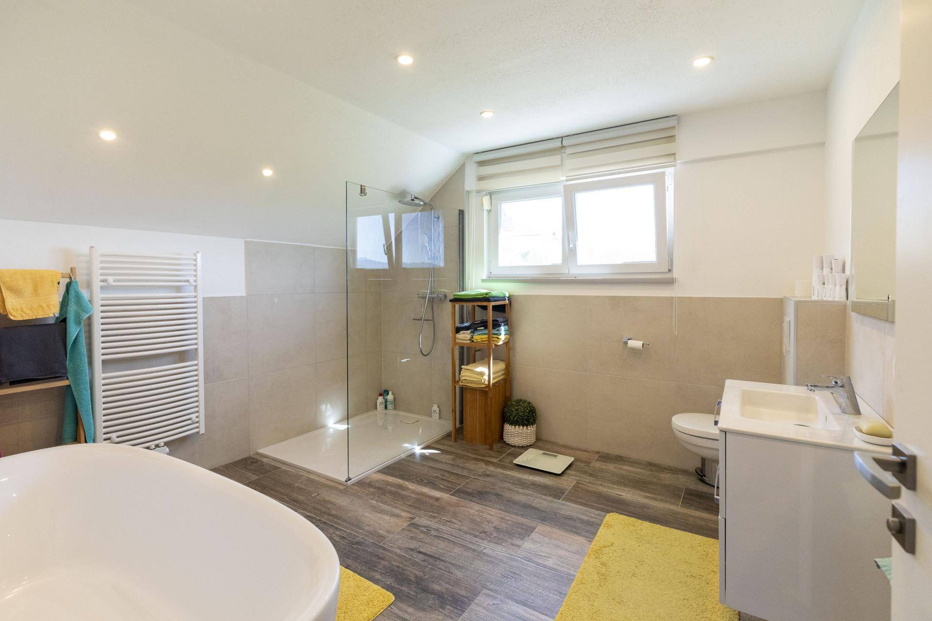 Modernes Badezimmer mit freistehender Badewanne, ebenerdiger Dusche und Fenster.