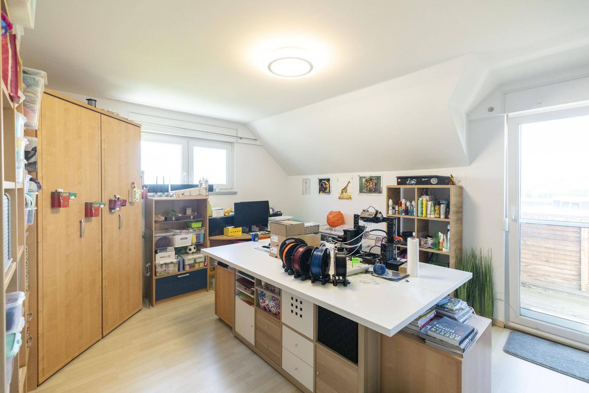 Geräumiges Arbeitszimmer mit großem Schreibtisch, Stauraum und Zugang zum Balkon.