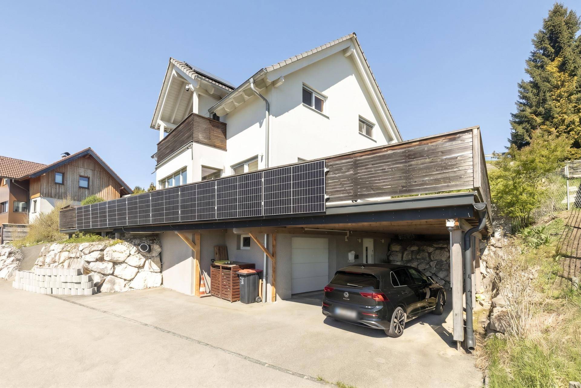 Vorderansicht des Hauses mit integriertem Carport und Photovoltaikanlage an der Fassade.