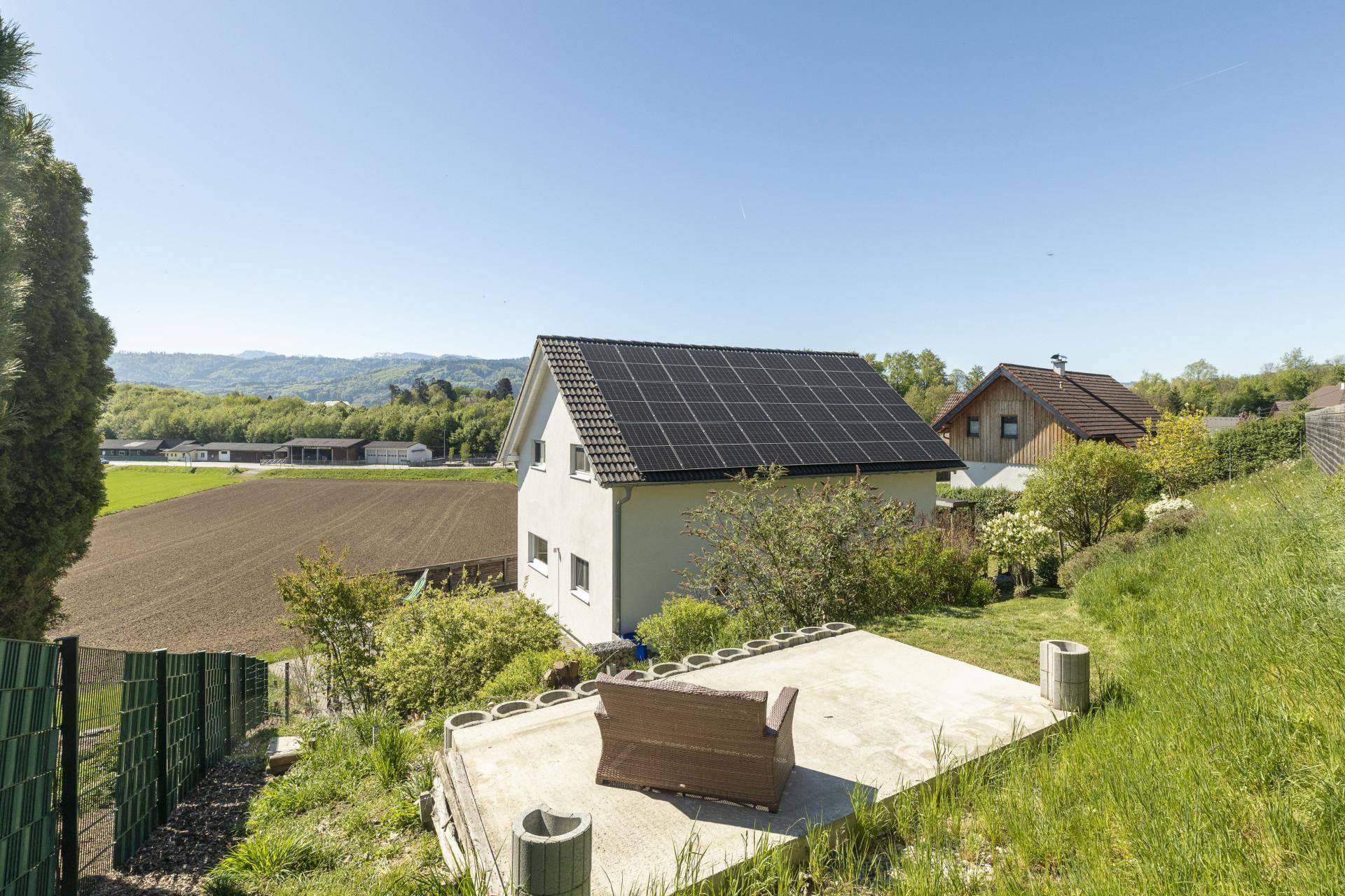 Rückansicht des Hauses mit Photovoltaikanlage auf dem Dach und einem kleinen Gartenbereich.