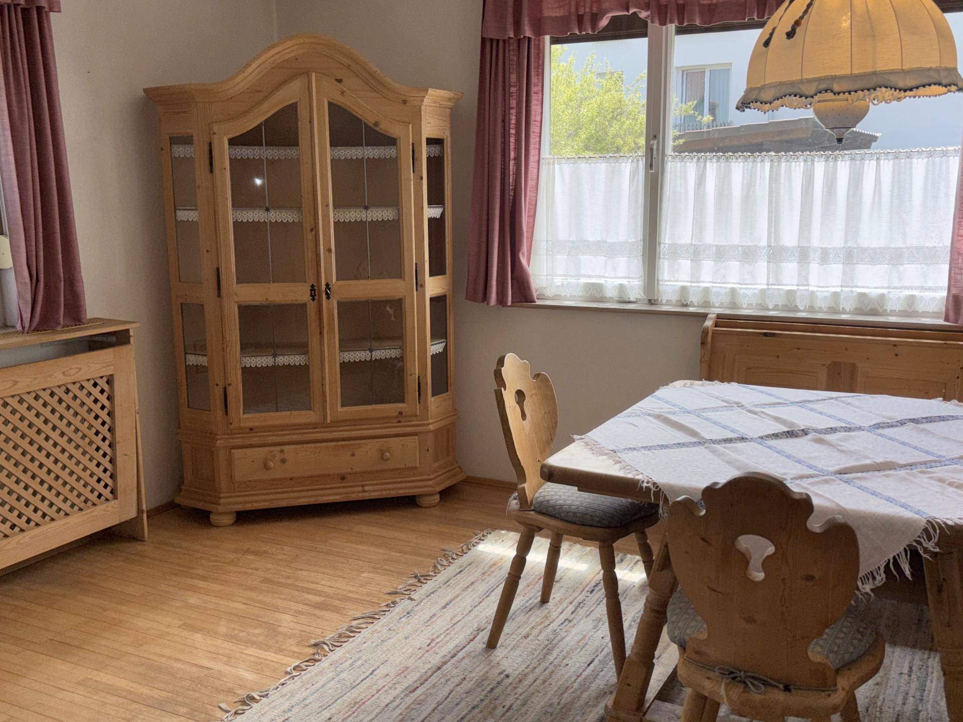 Essbereich im Landhausstil mit Holztisch, Stühlen und einem traditionellen Vitrinenschrank.