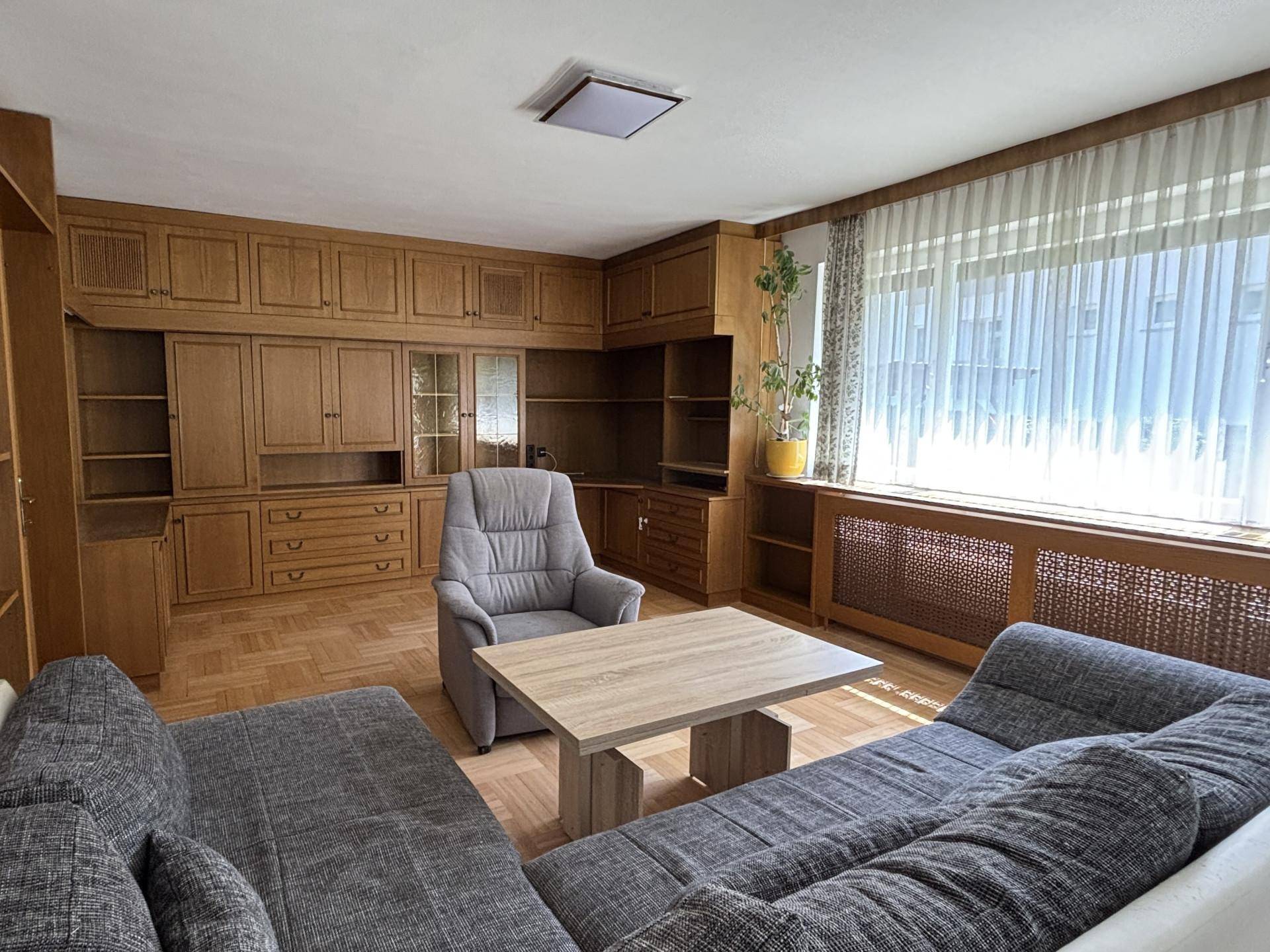 Gemütliches Wohnzimmer mit Holzvertäfelung, Parkettboden und großem Fenster.