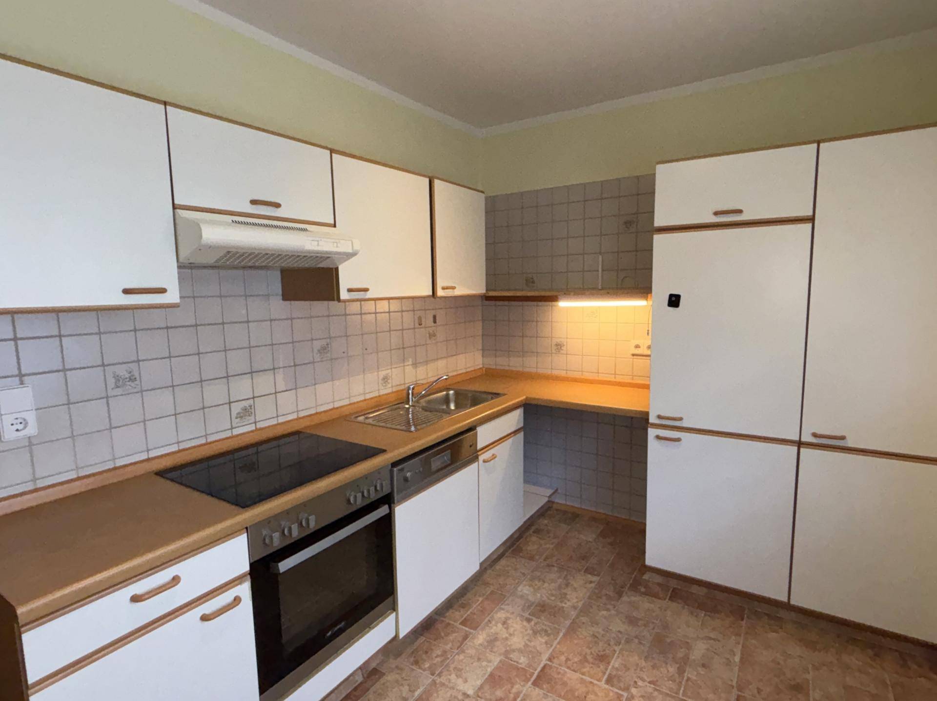 Funktionale Küche mit weißen Schränken, Fliesenrückwand und integrierten Geräten.