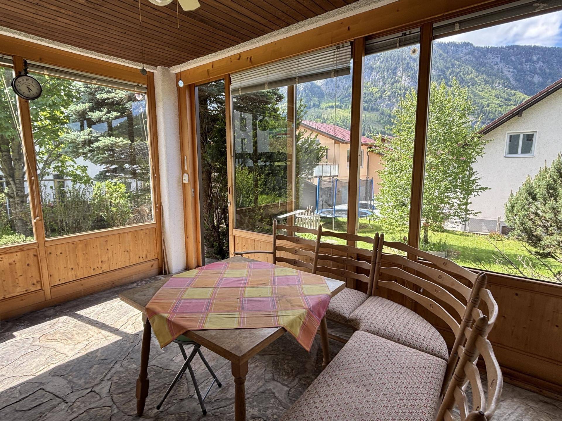 Heller Wintergarten mit Bergblick, Holzverkleidung und rustikalem Steinfliesenboden.